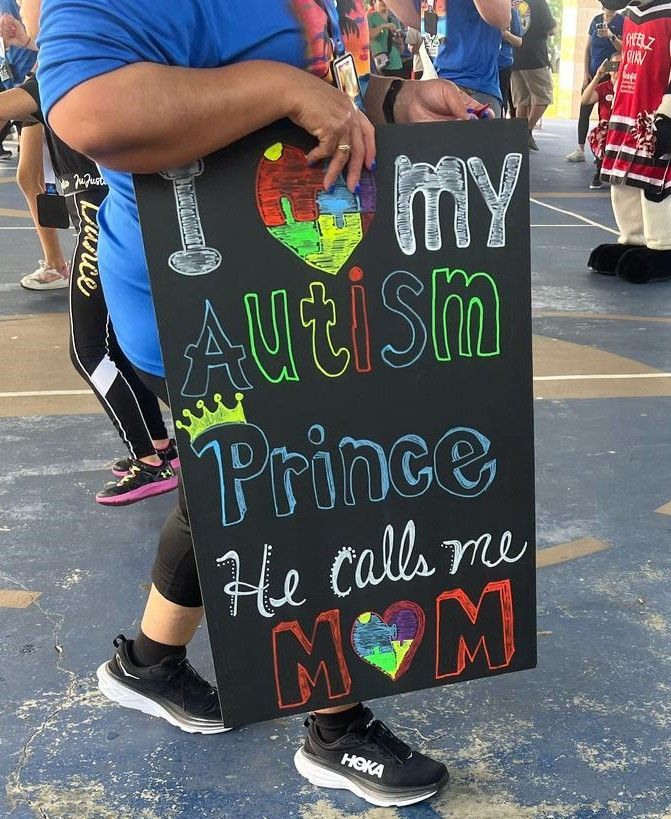 A person holding a sign that says i love my autism prince he calls me mom