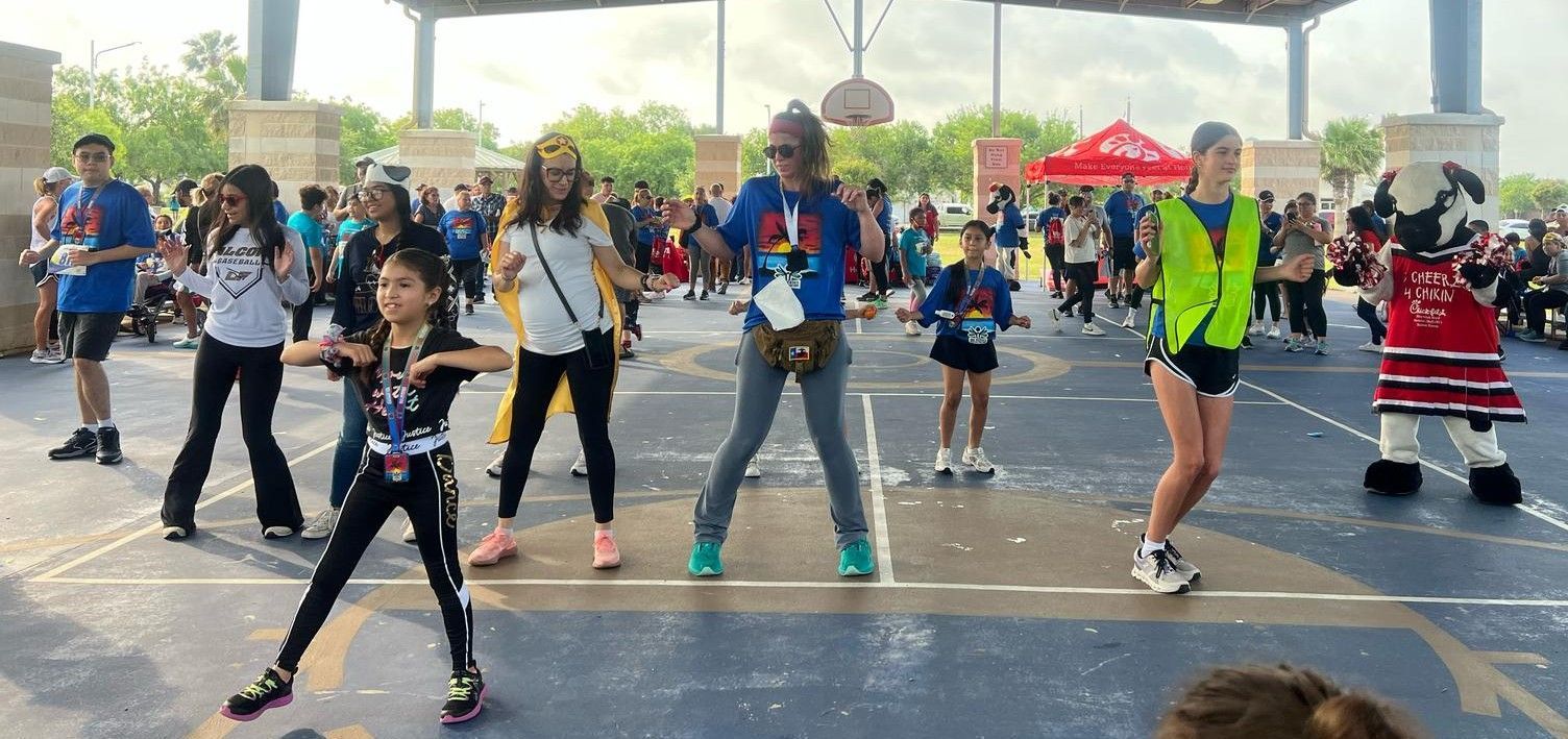 A group of people are dancing on a basketball court.