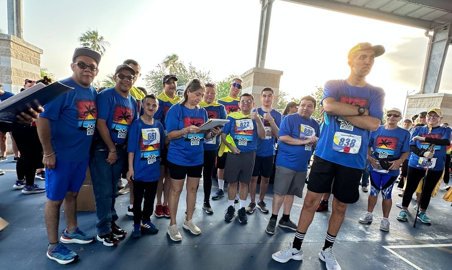 A group of people wearing blue shirts are standing in a parking lot.
