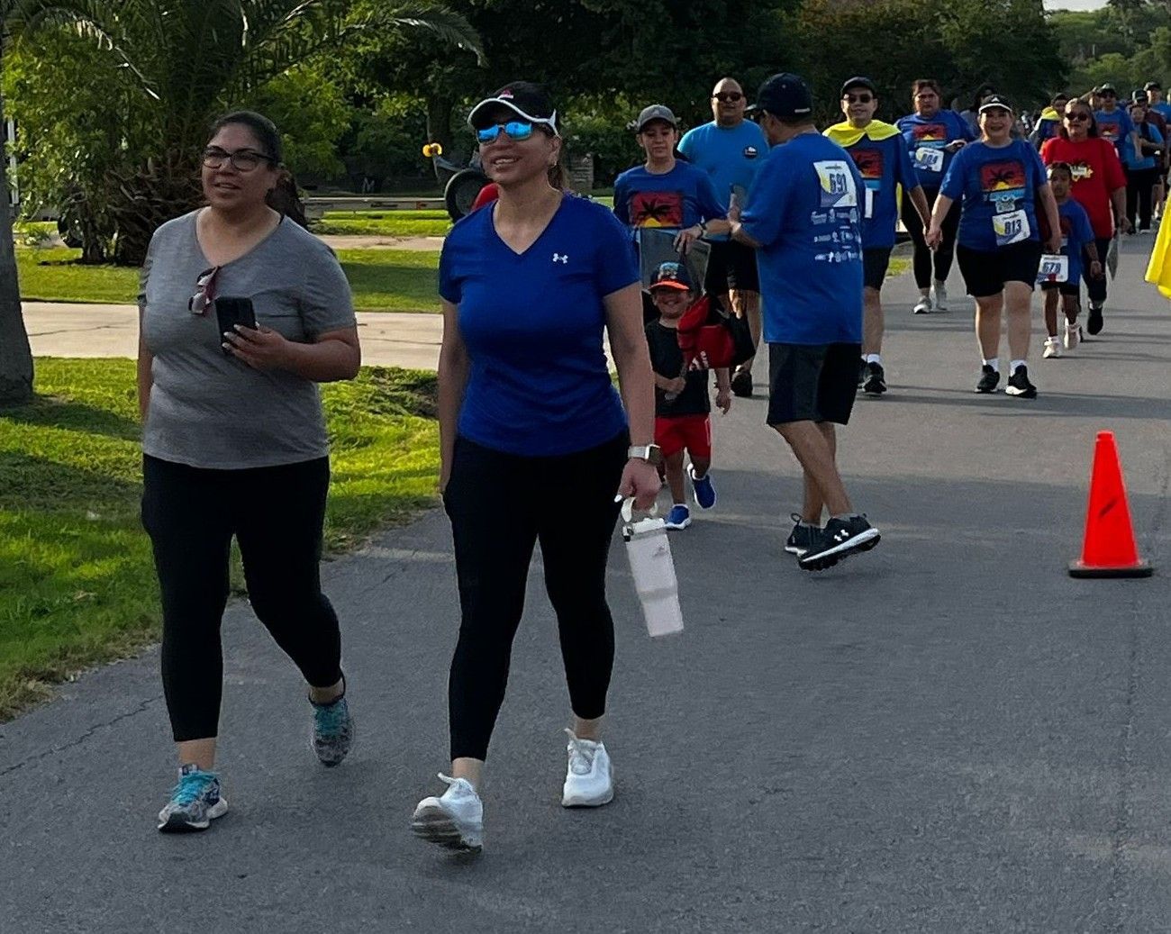 A group of people are walking down a path and one woman is wearing sunglasses