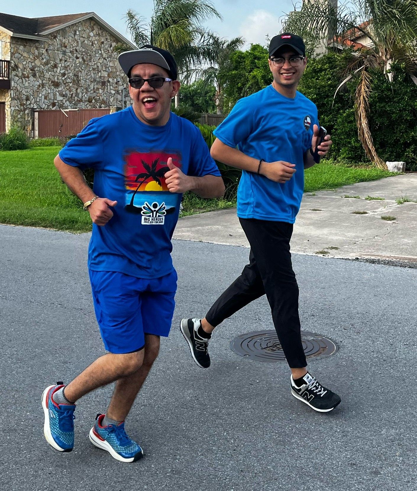 Two men in blue shirts are running down a street