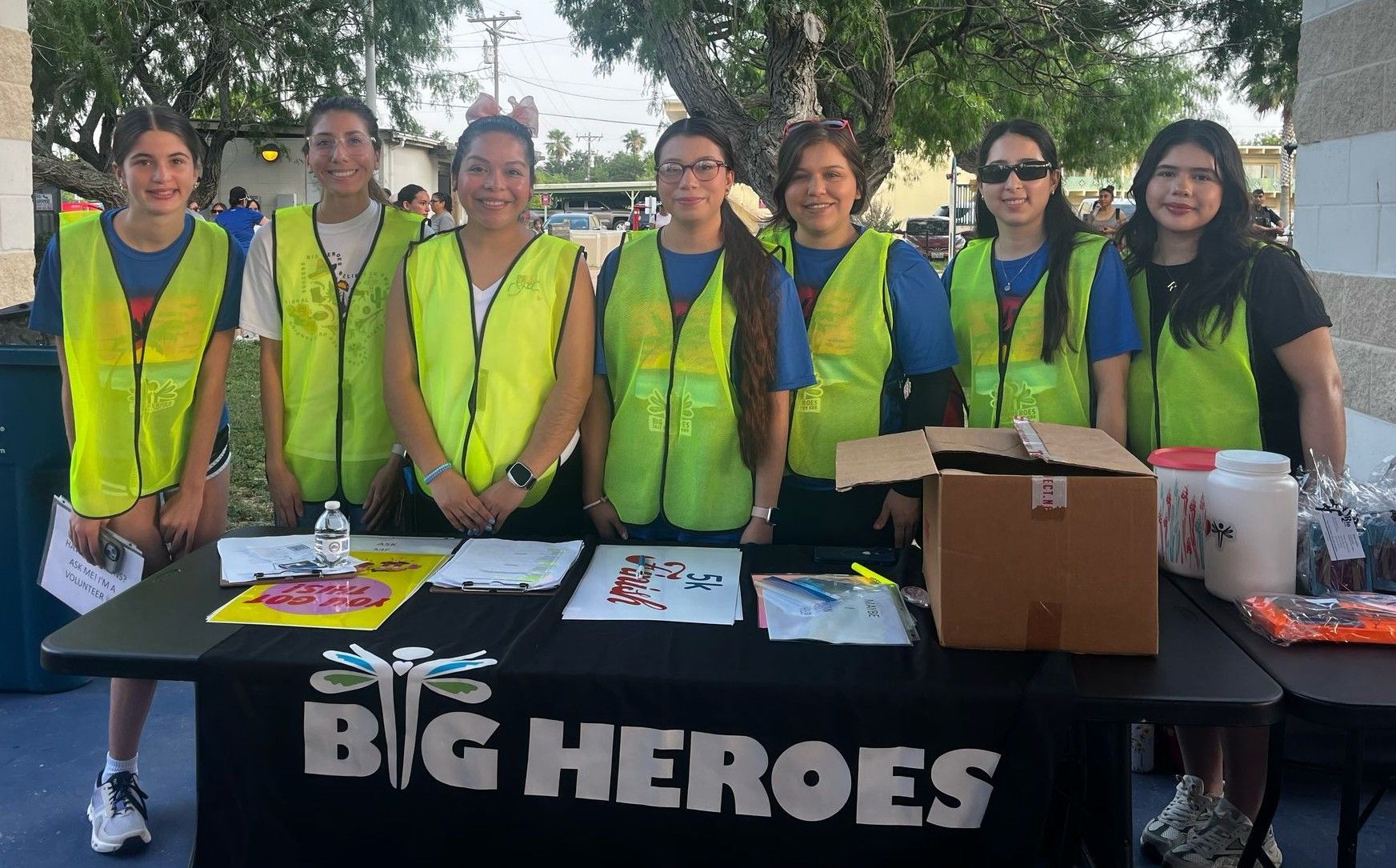 A group of people standing around a table that says big heroes.