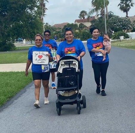 A group of women are walking down a street with a baby in a stroller.