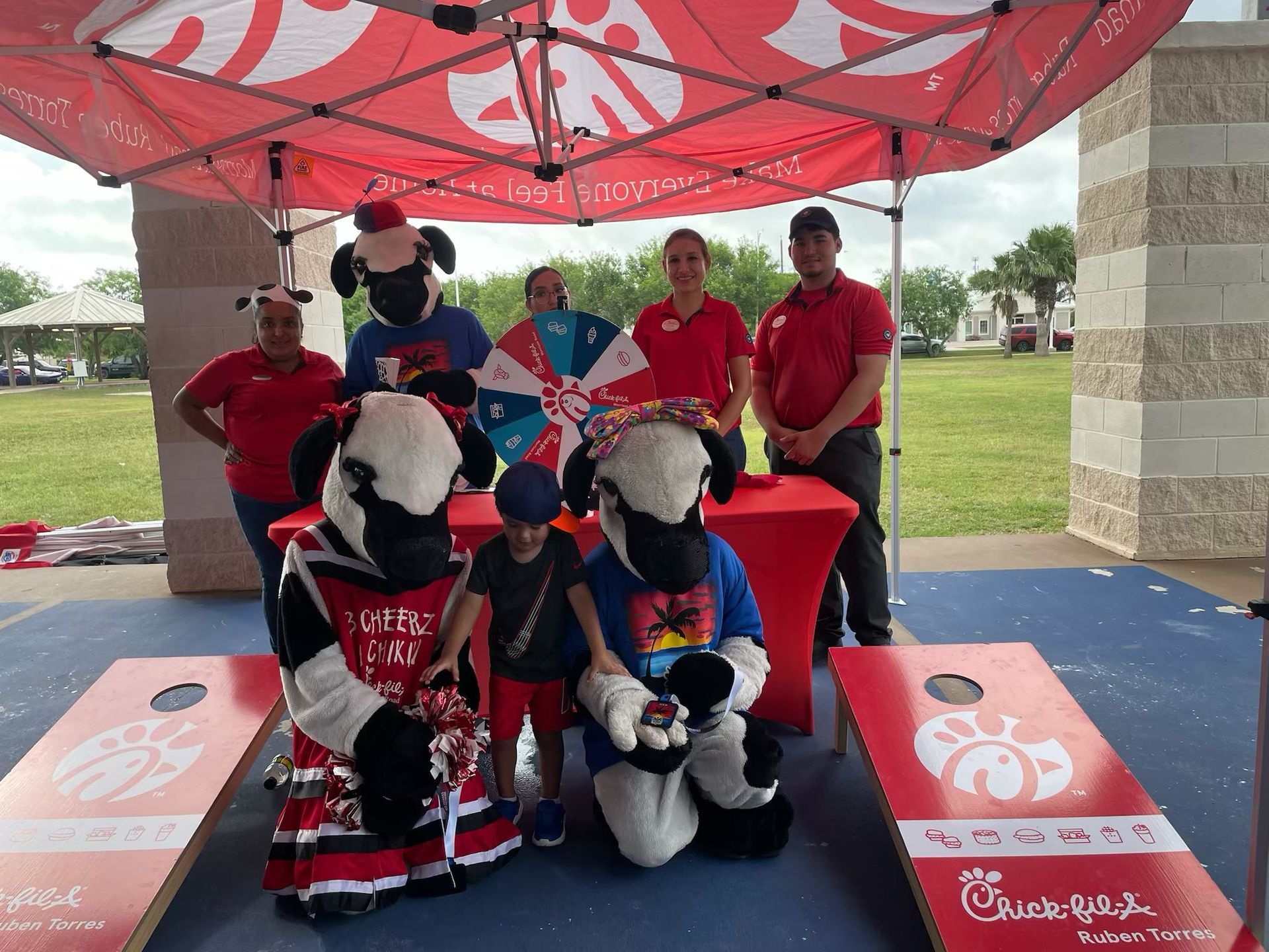 A group of people standing around a table with chick fil a mascots