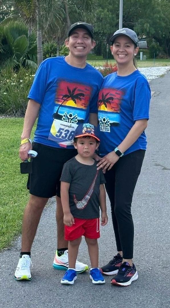 A man , woman and child are standing next to each other on a sidewalk.