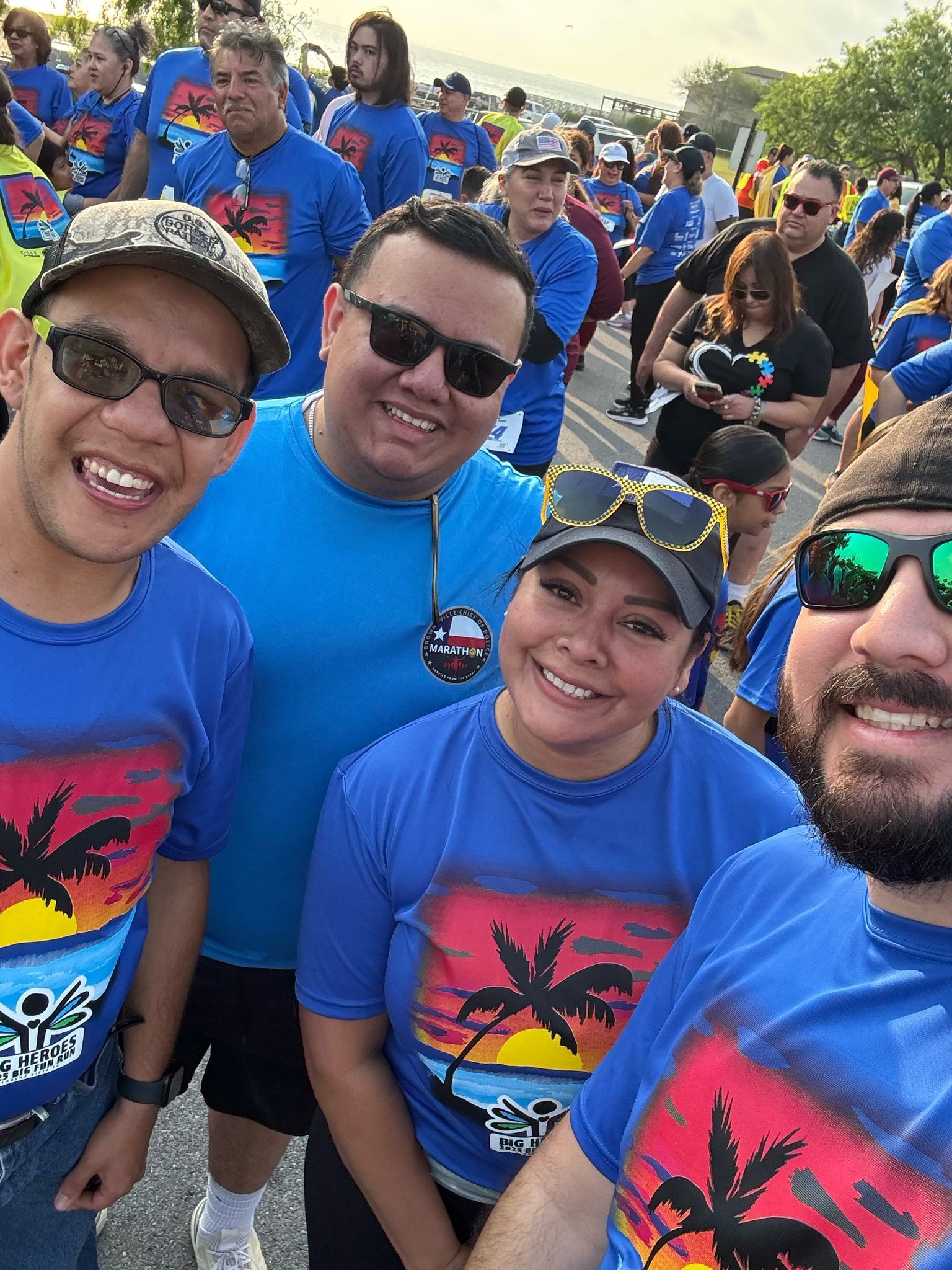 A group of people wearing blue shirts with palm trees on them are posing for a picture.