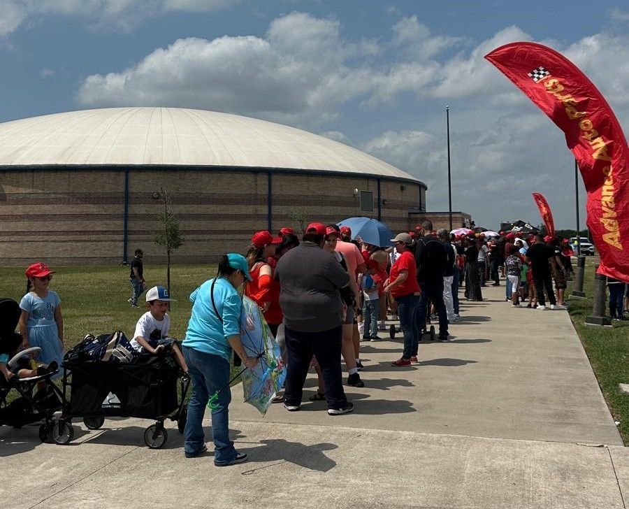 A group of people standing on a sidewalk with a red flag that says advance