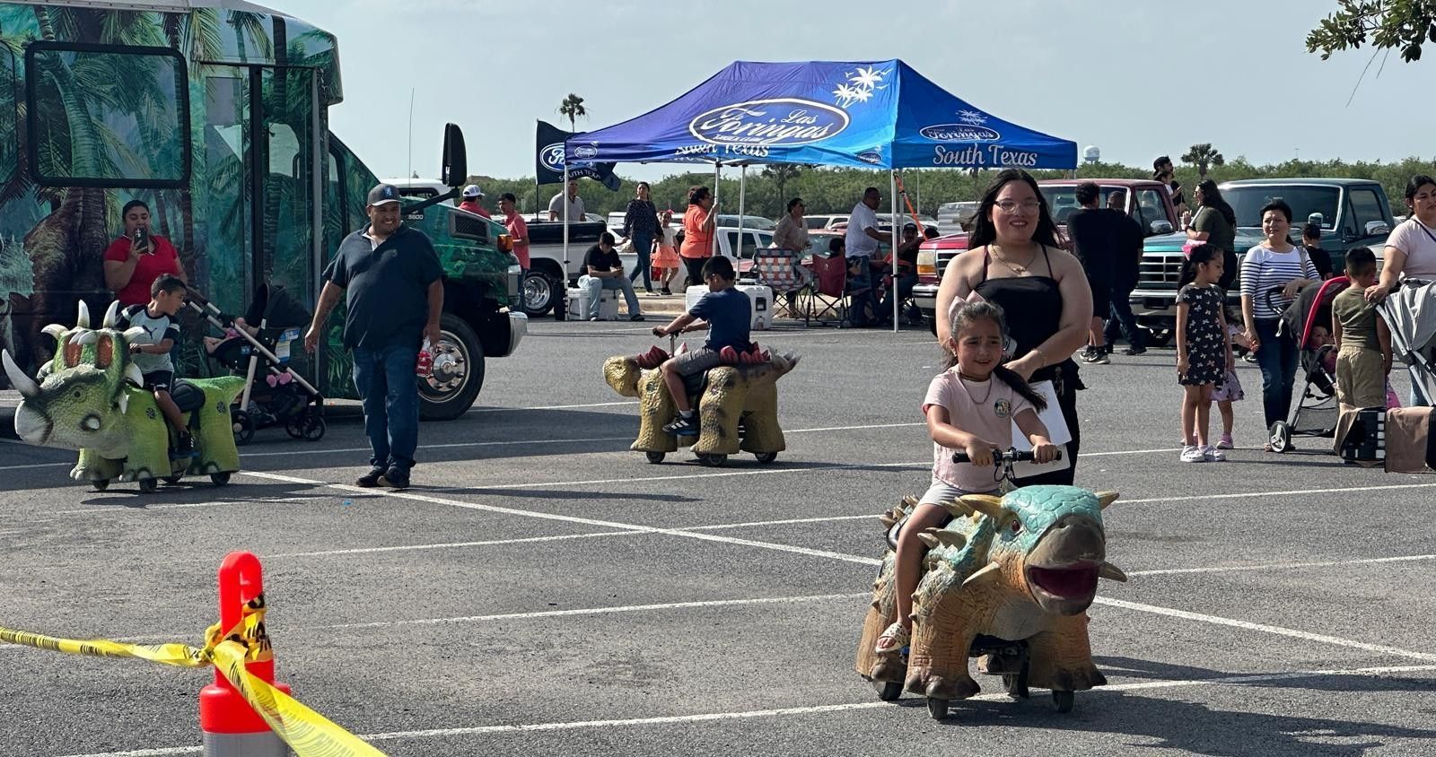 A group of people are riding toy horses in a parking lot.
