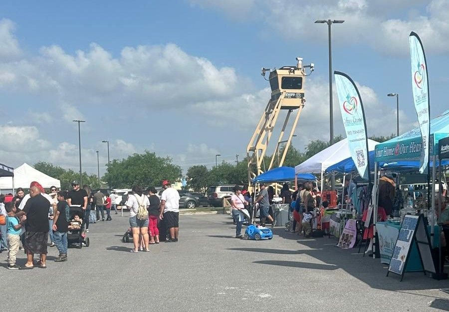 A group of people are standing in a parking lot at a market.