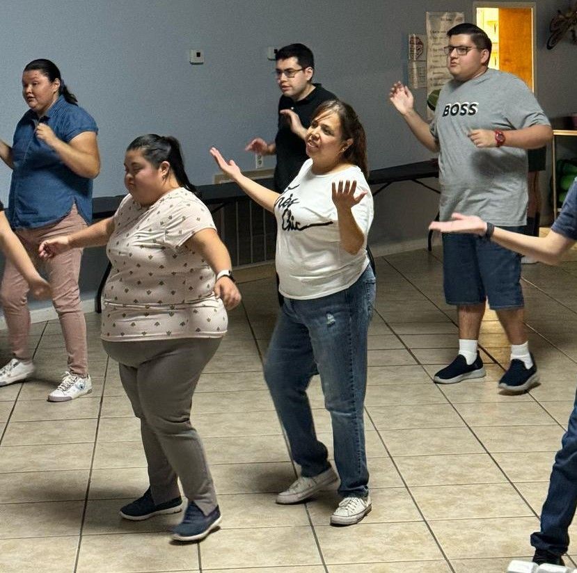 A group of people are dancing and one man is wearing a shirt that says boss