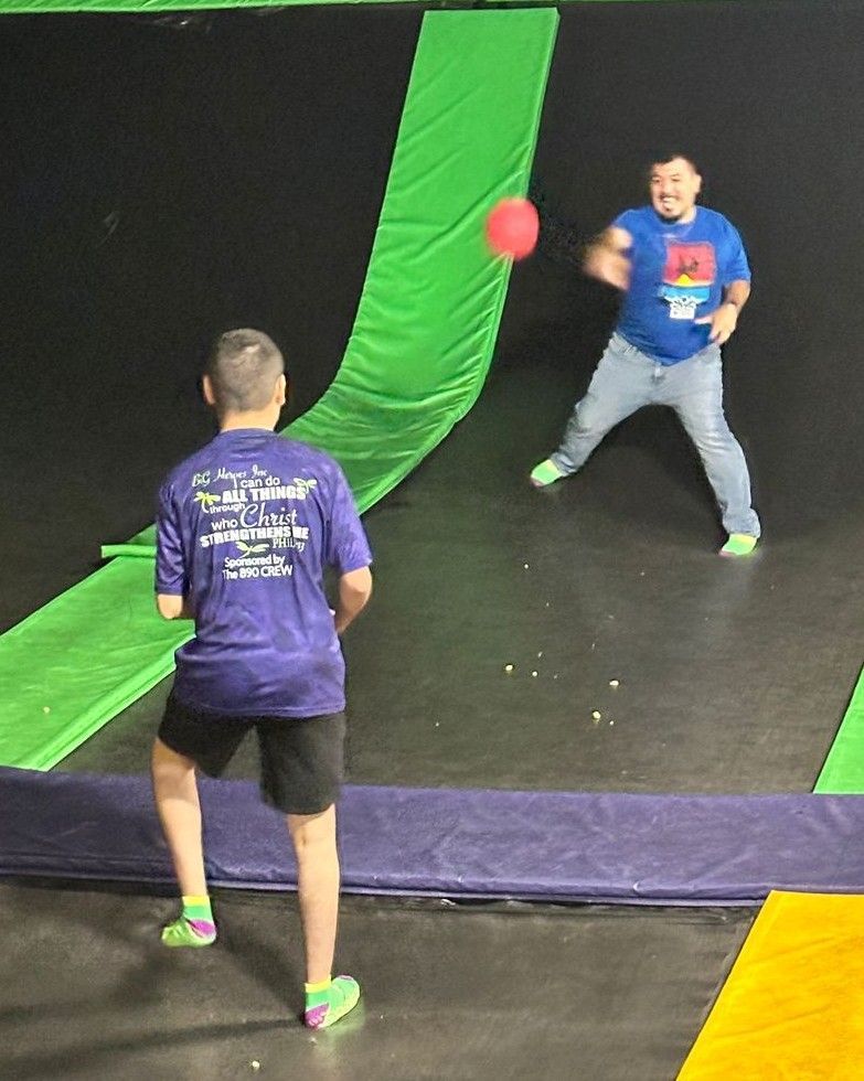 Two boys are playing dodgeball on a trampoline.