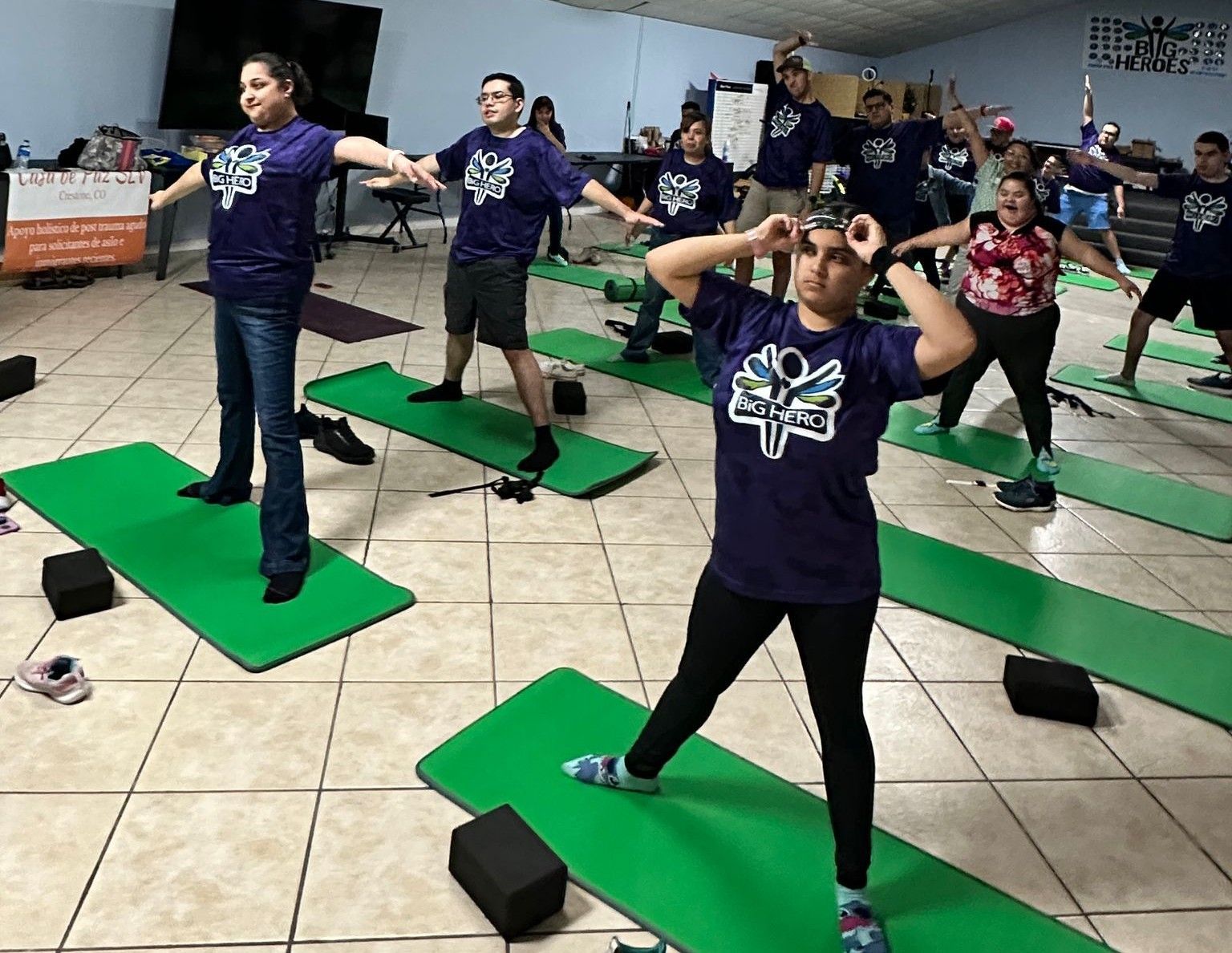 A group of people are doing yoga on green mats