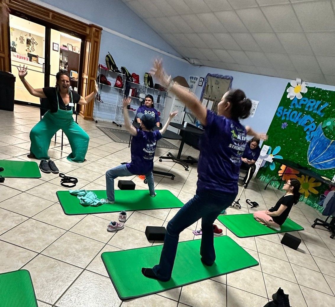 A group of people are doing yoga on green mats in a room