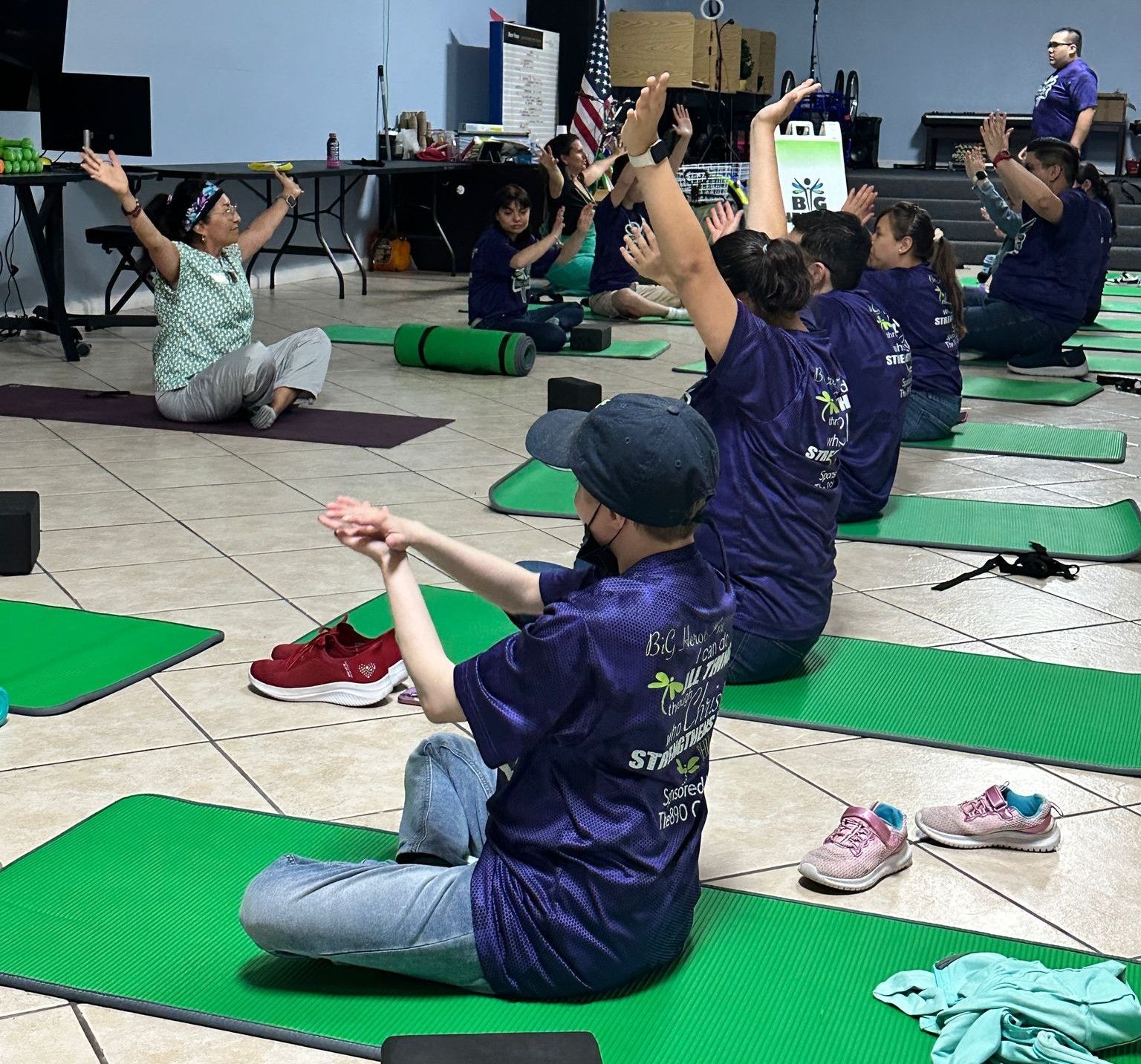 A group of people are sitting on yoga mats with their arms in the air