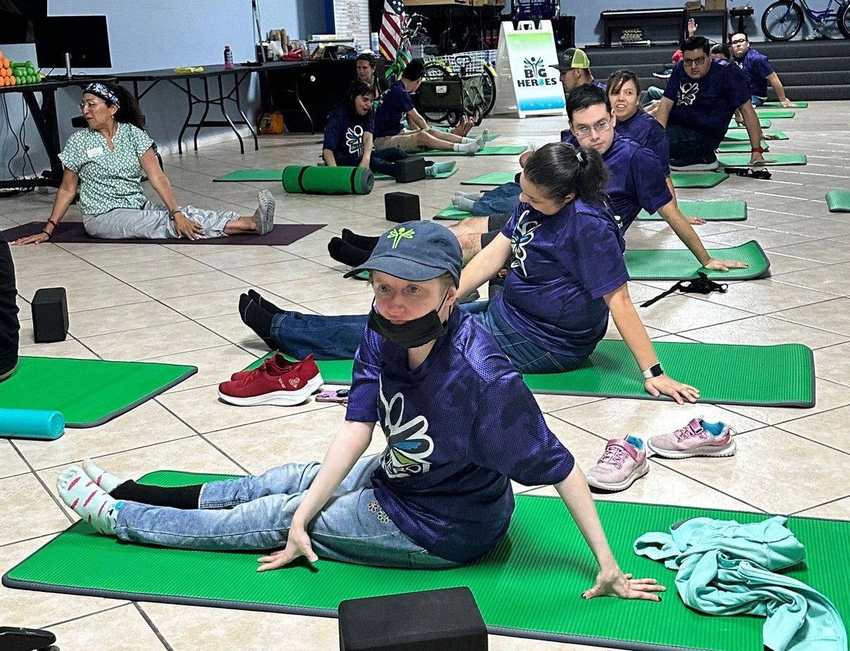 A group of people are sitting on green yoga mats.