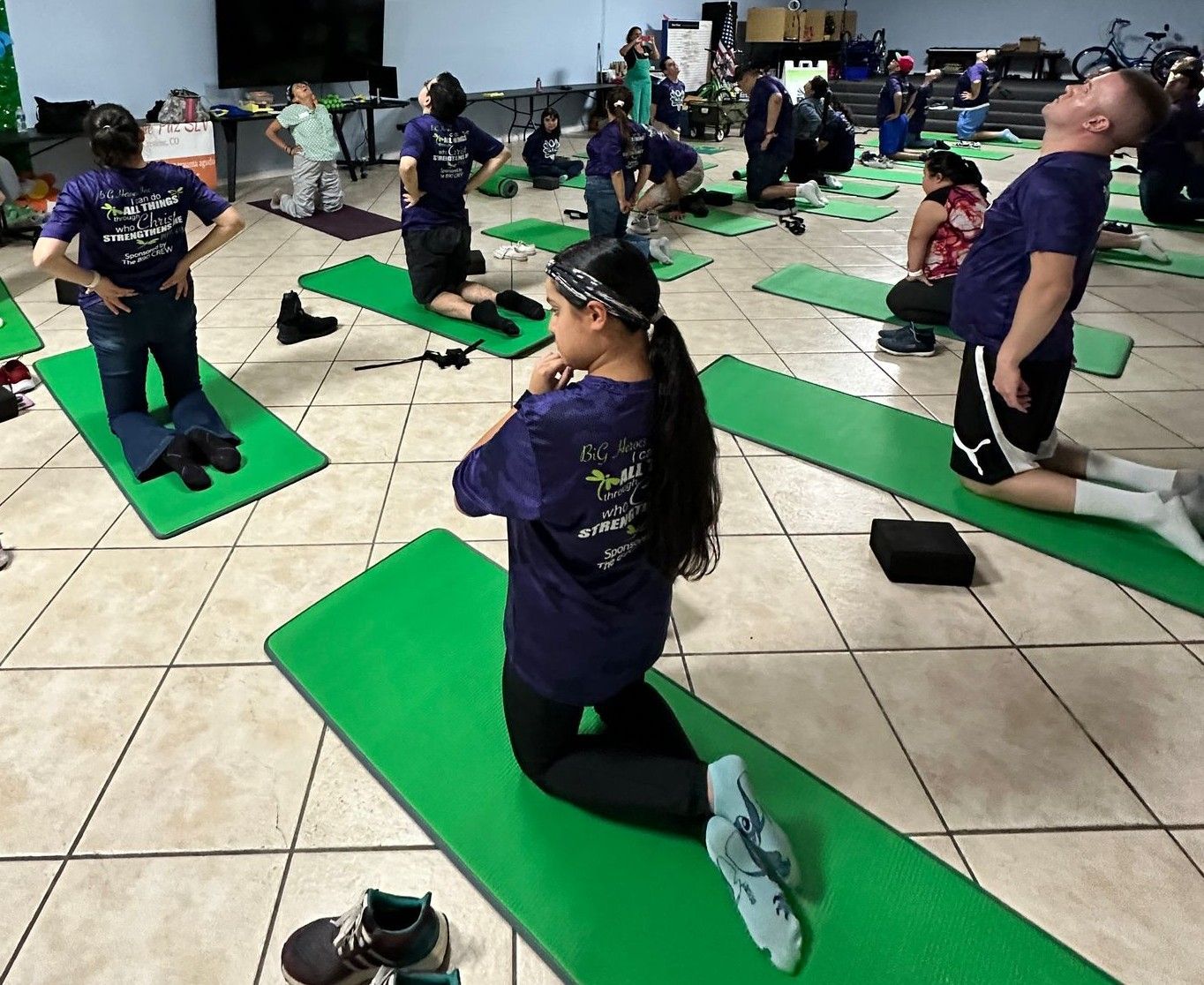 A group of people are doing yoga on green mats