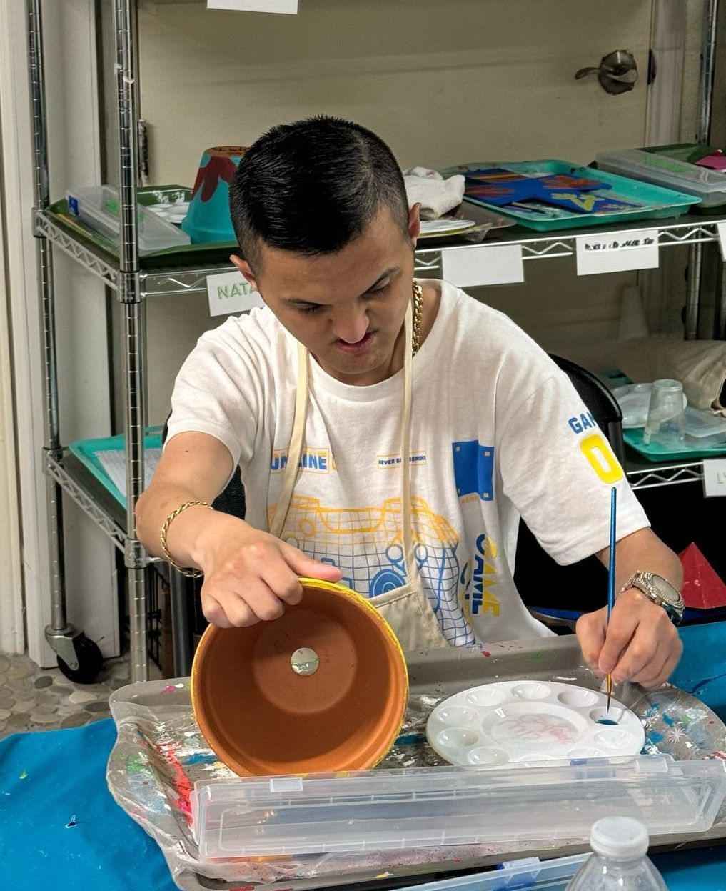 A man in a white shirt is painting a pot