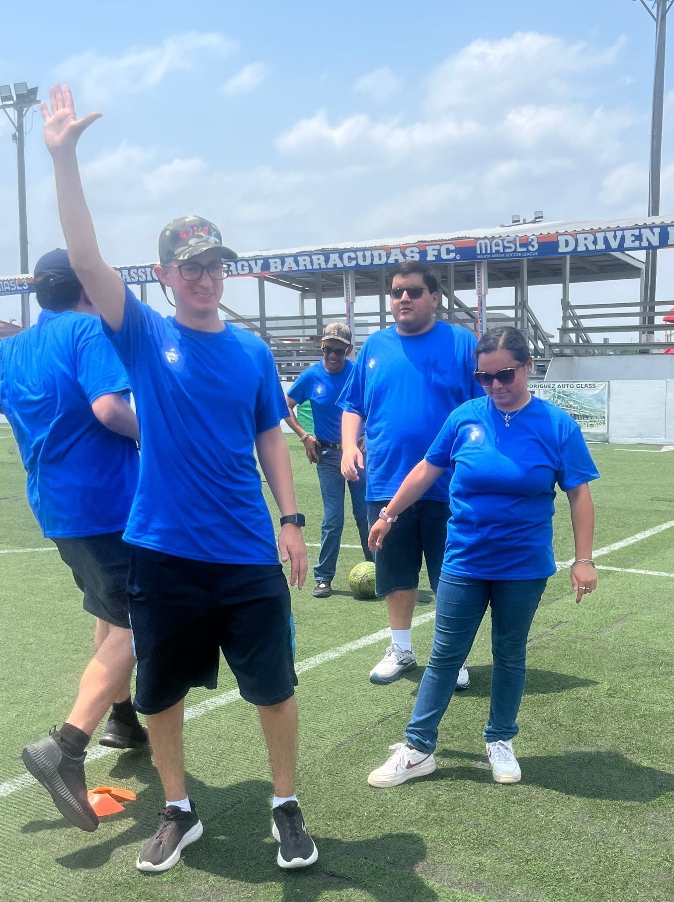 A group of people wearing blue shirts are standing on a field