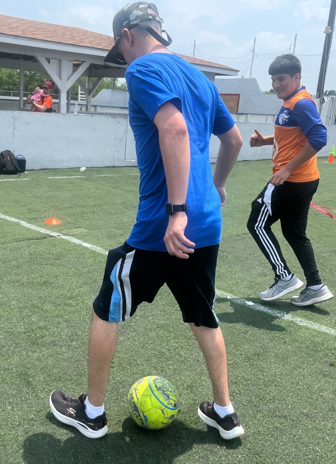 A man in a blue shirt is kicking a soccer ball