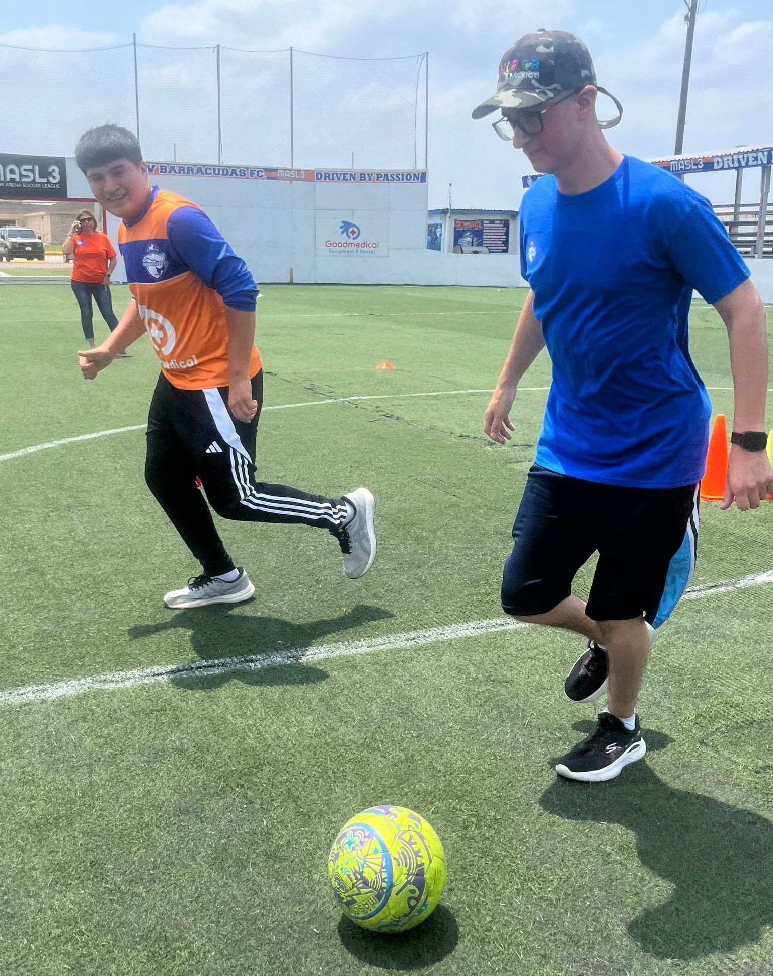 A man in a blue shirt is kicking a soccer ball