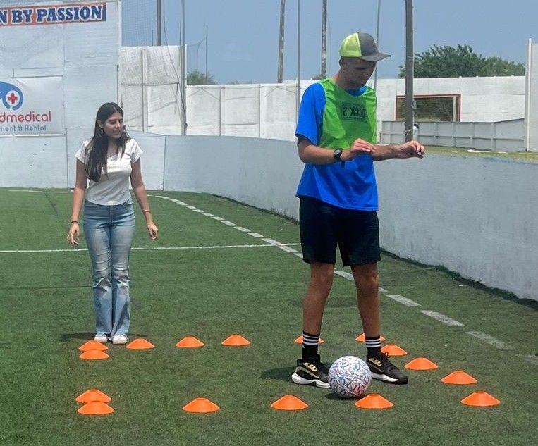 A man and a woman are playing soccer in front of a sign that says very passion