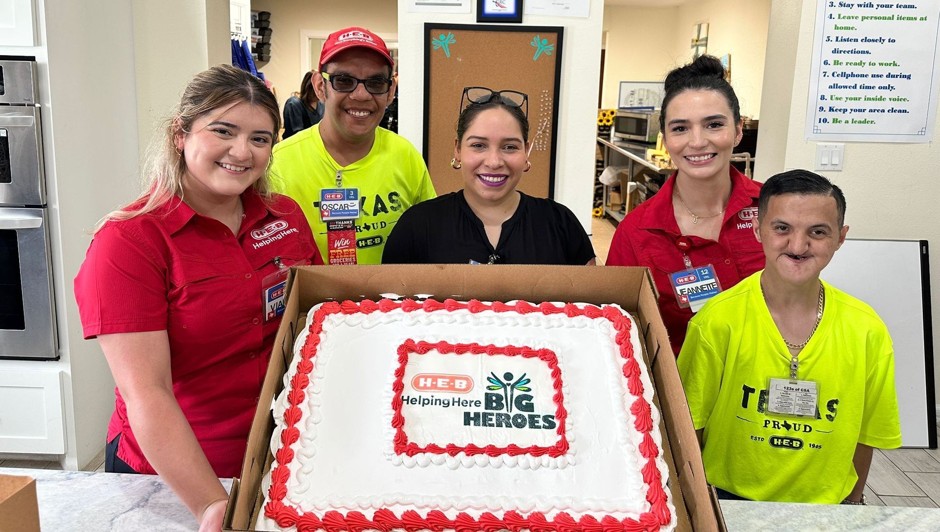 A group of people are standing around a large cake.