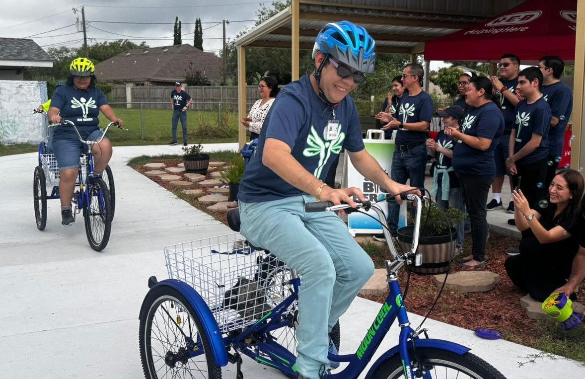 A group of people are riding tricycles on a sidewalk.