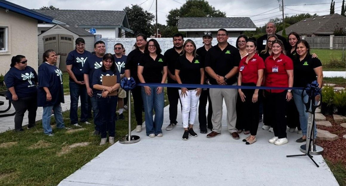 A group of people are standing in front of a ribbon cutting ceremony.