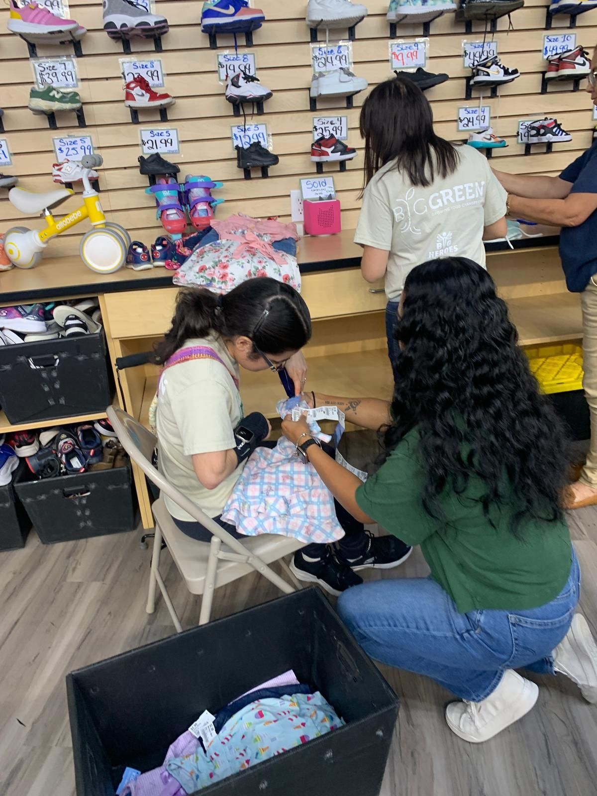 People sorting and packing clothing in a shoe store, with shoes on display on the wall.