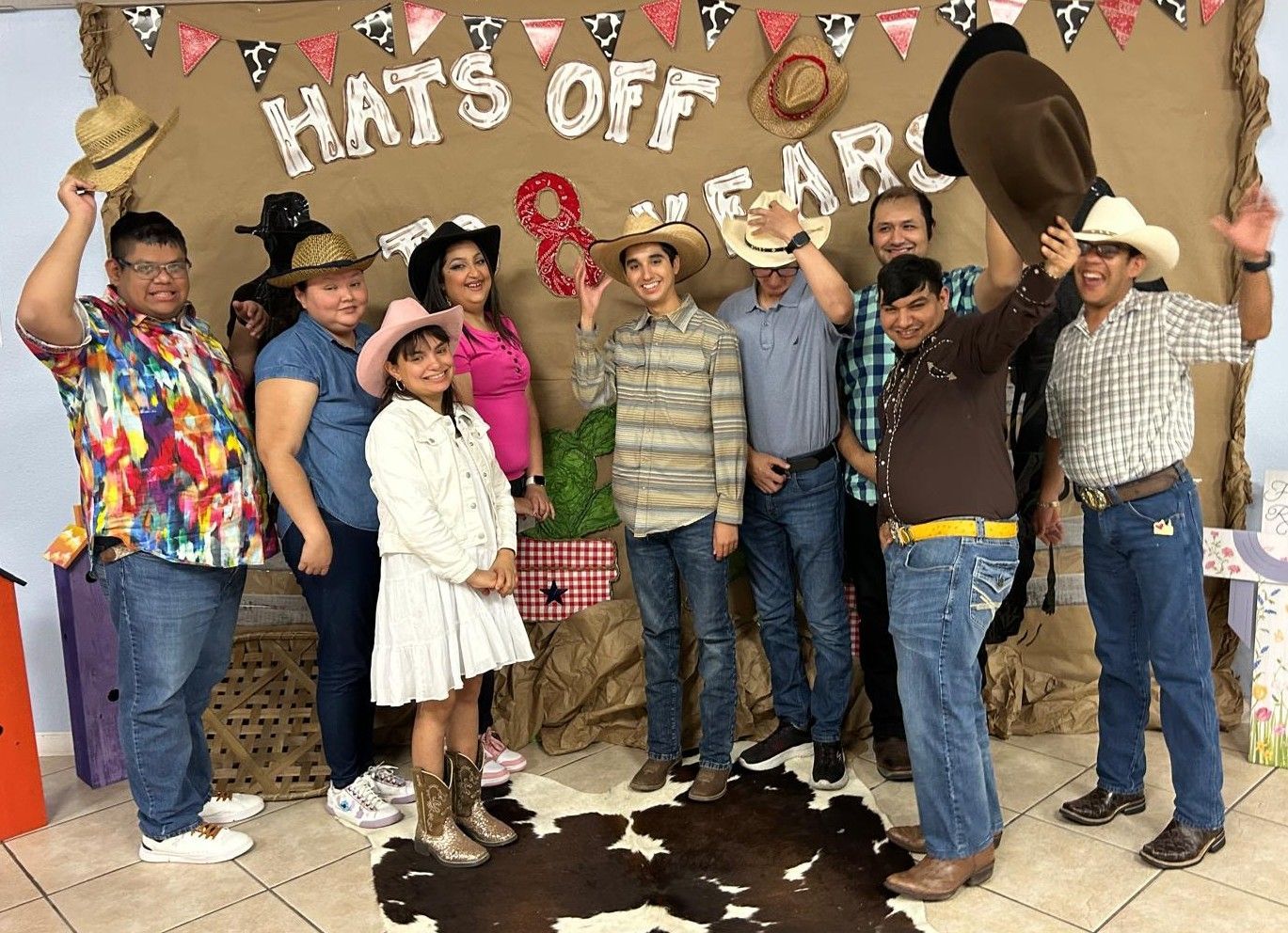 Group of people in cowboy hats celebrating, posing in front of a