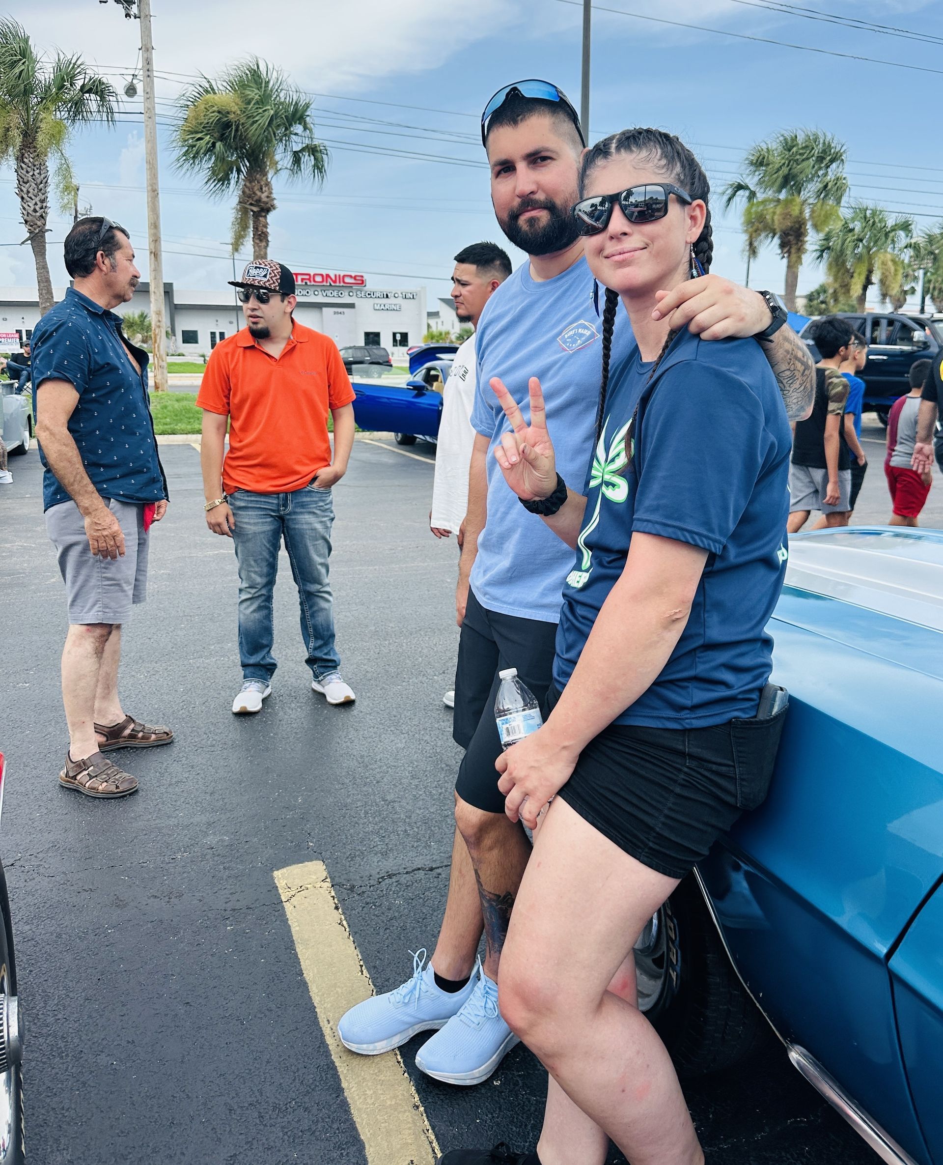 A man and woman are posing for a picture next to a blue car