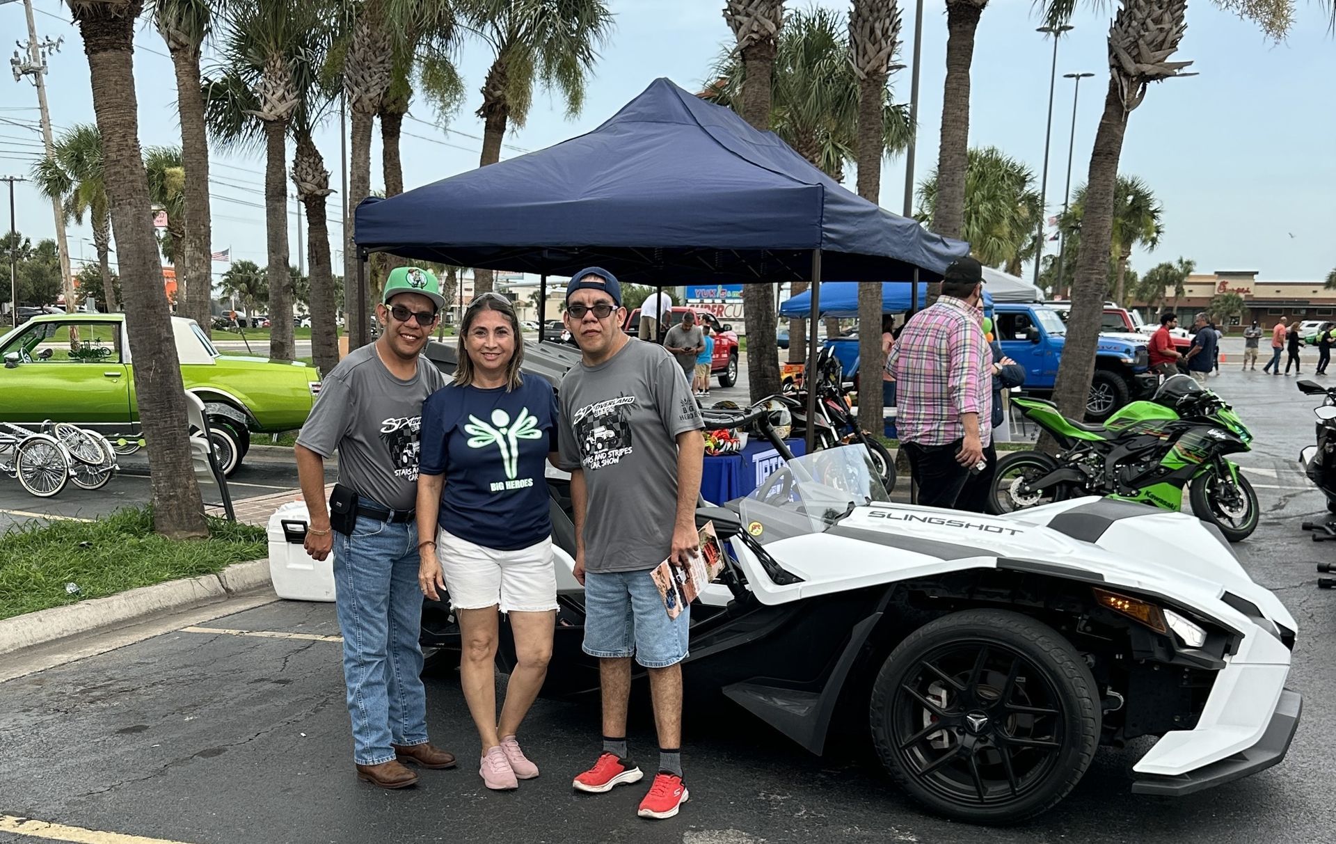 A group of people are standing in front of a slingshot car.