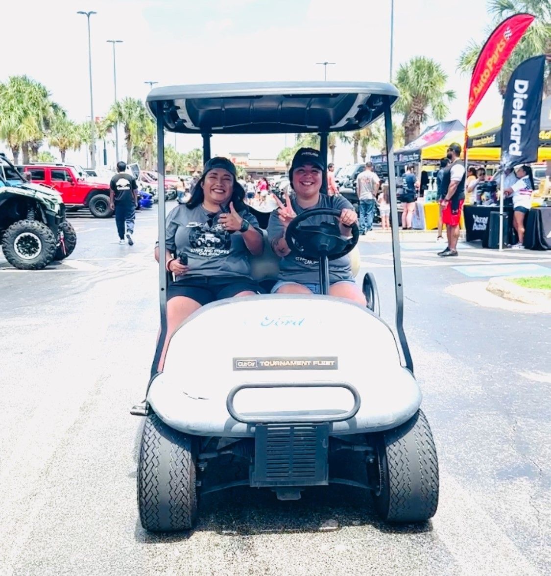 Two women are riding in a golf cart on a street.