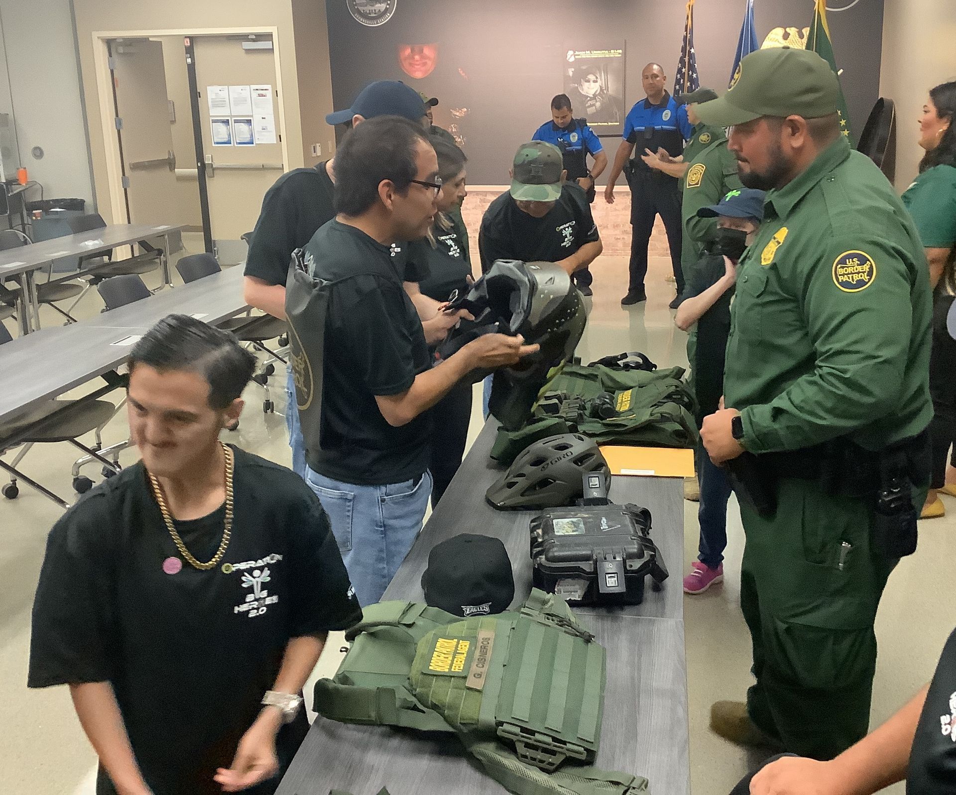 A group of men are standing around a table with a vest that says ' us army ' on it
