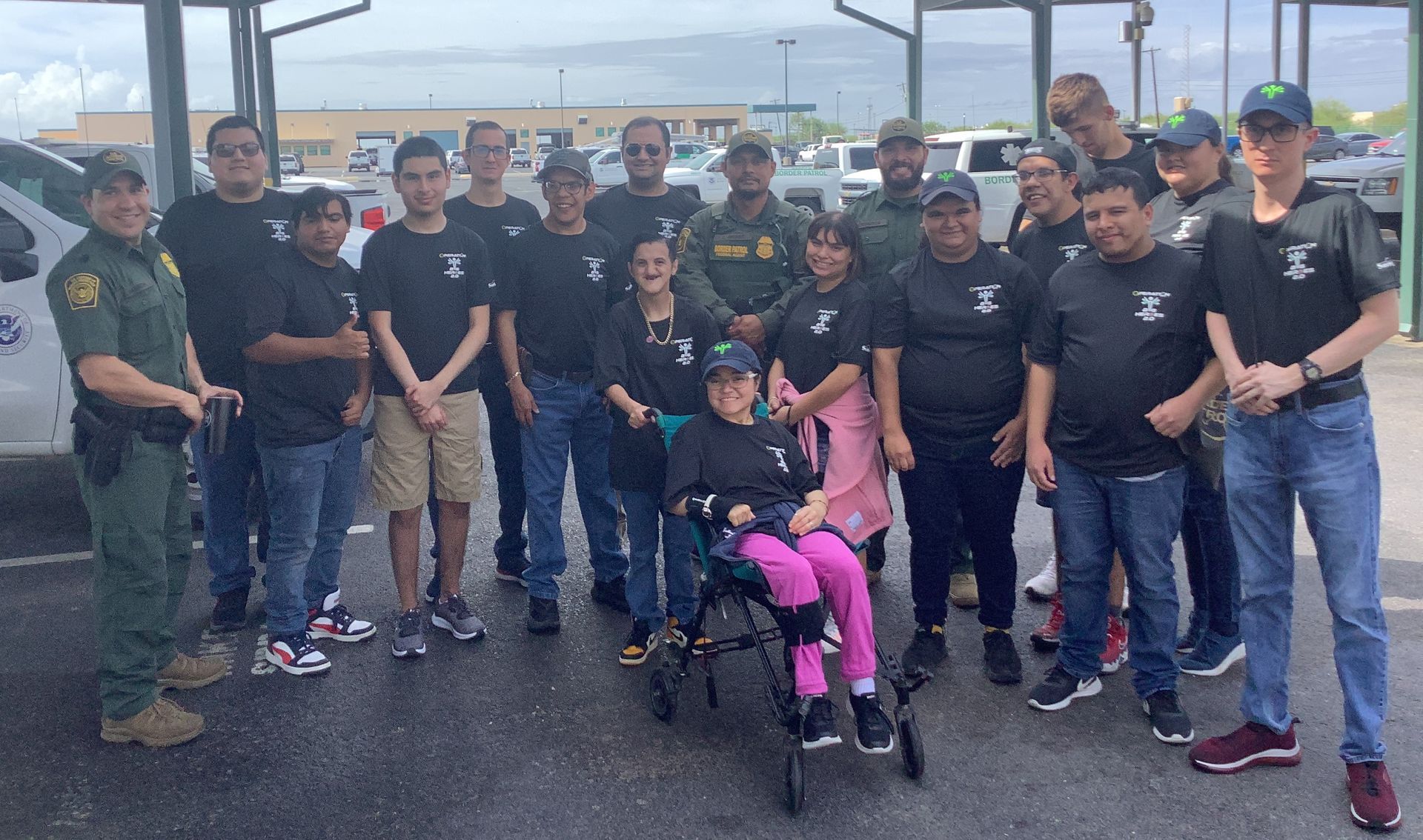 A group of people are posing for a picture with a girl in a wheelchair.