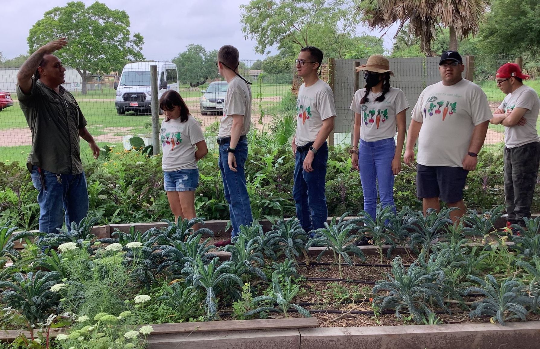 A group of people are standing in a garden looking at plants.