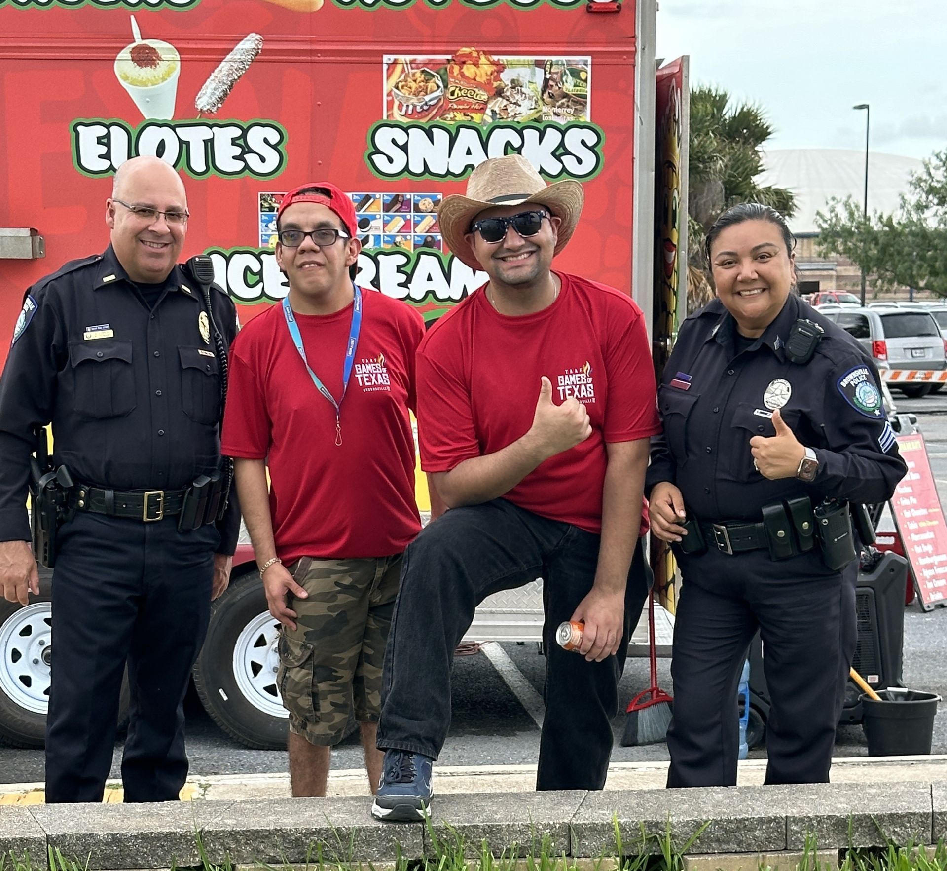 A group of people standing in front of a truck that says elotes snacks