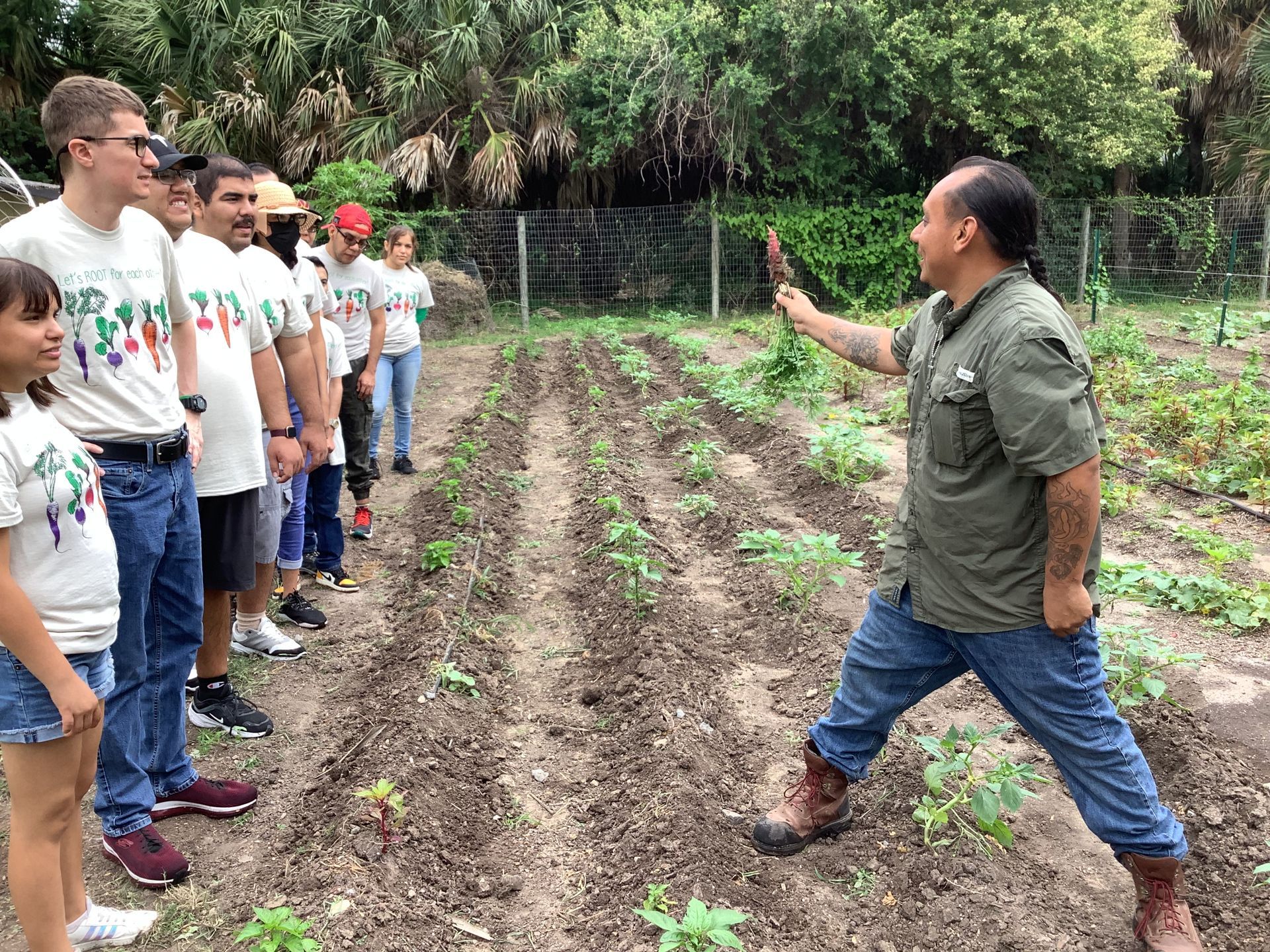 A man is standing in a garden talking to a group of people.