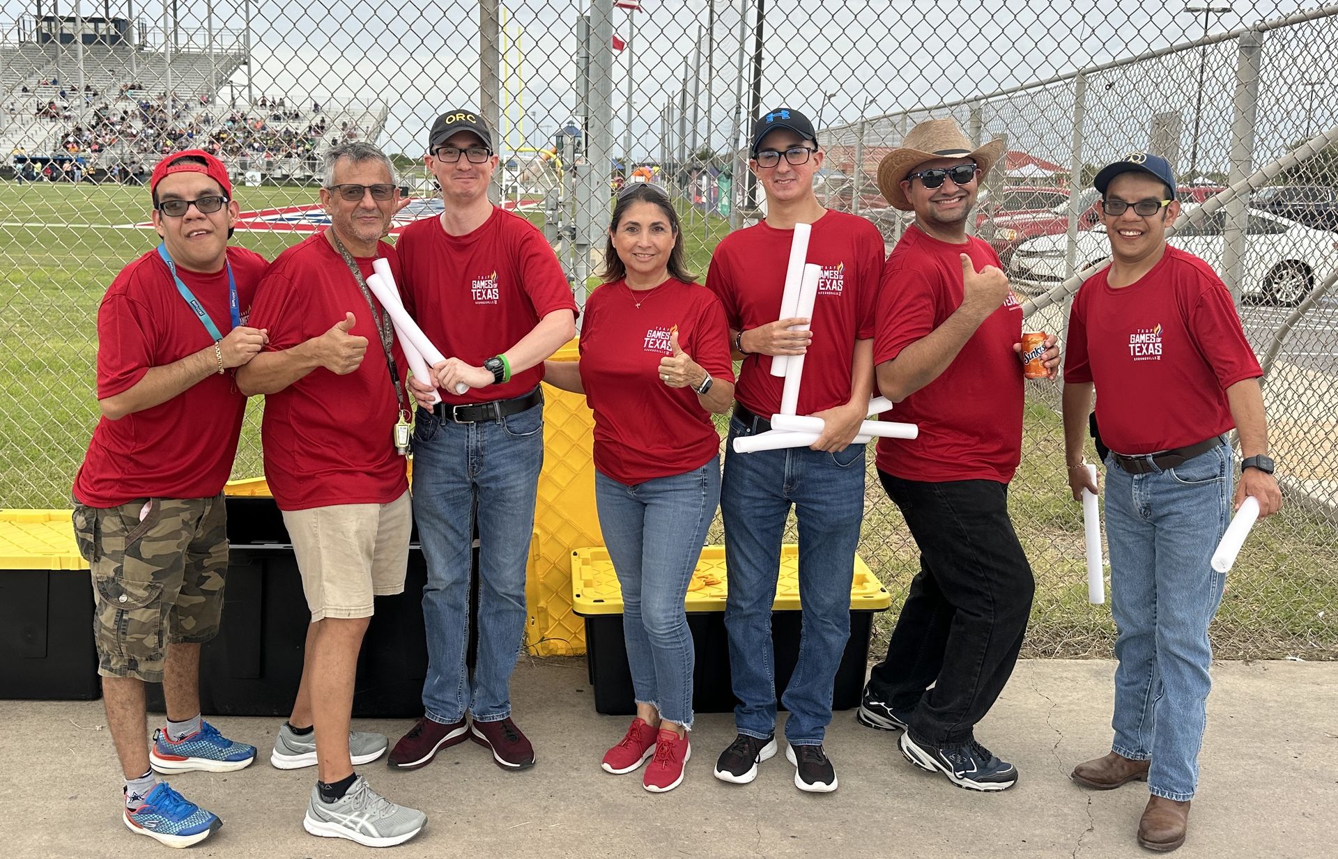 A group of people in red shirts are standing next to each other on a sidewalk.