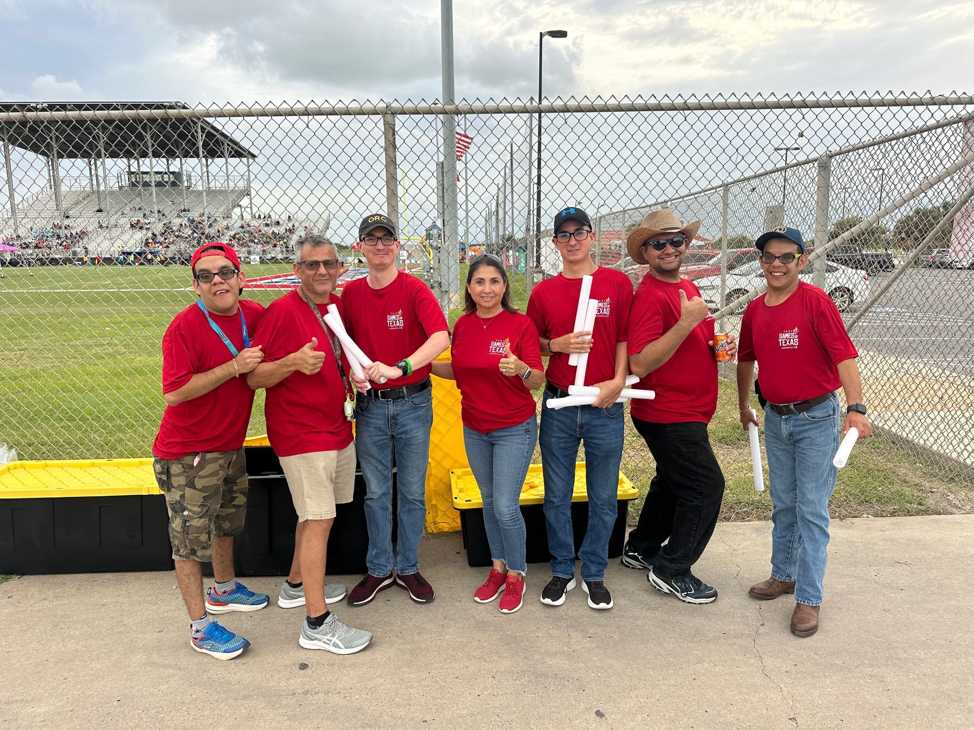 A group of people in red shirts are standing next to each other on a sidewalk.