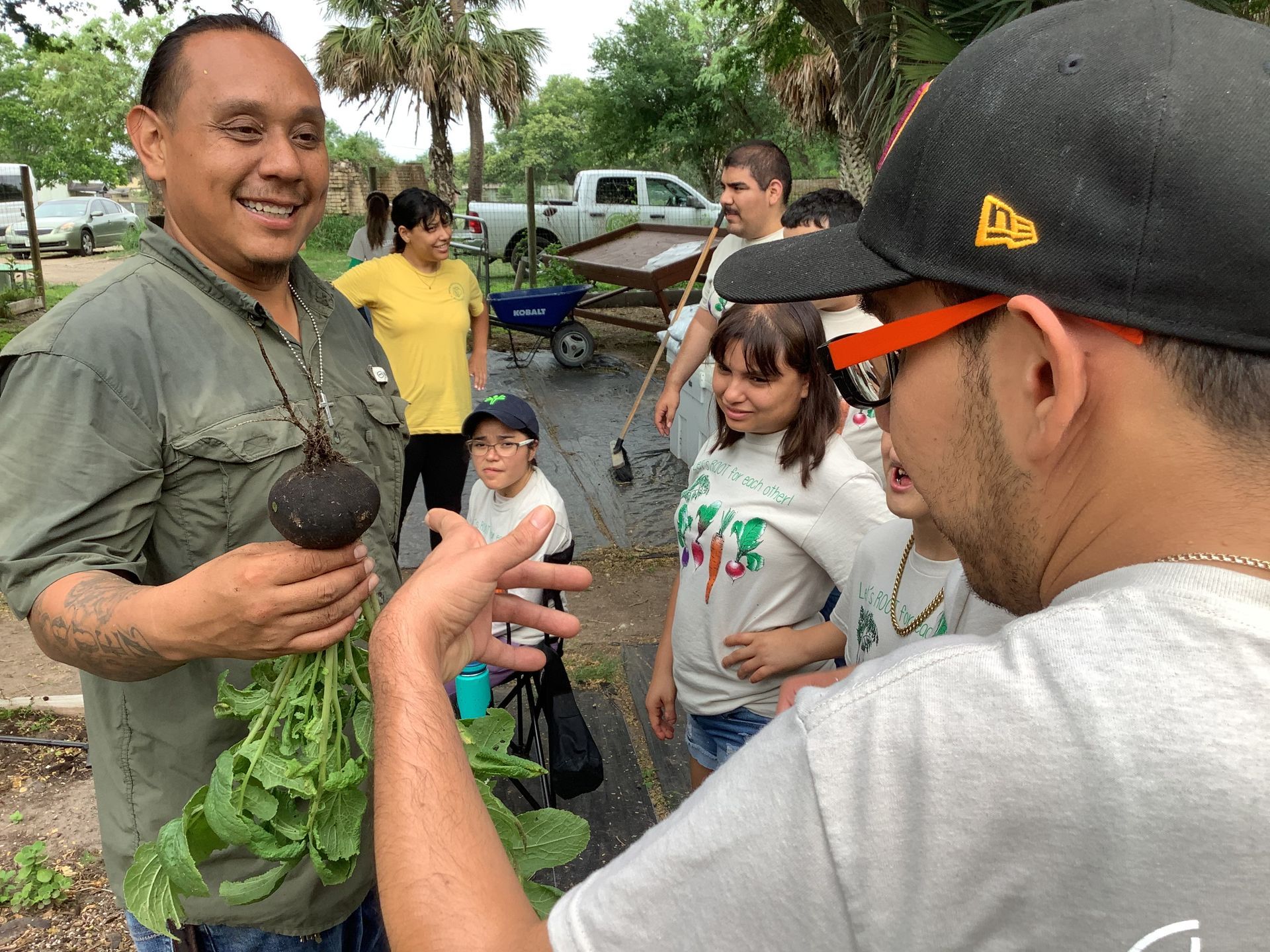 A group of people are standing around a man holding a radish.