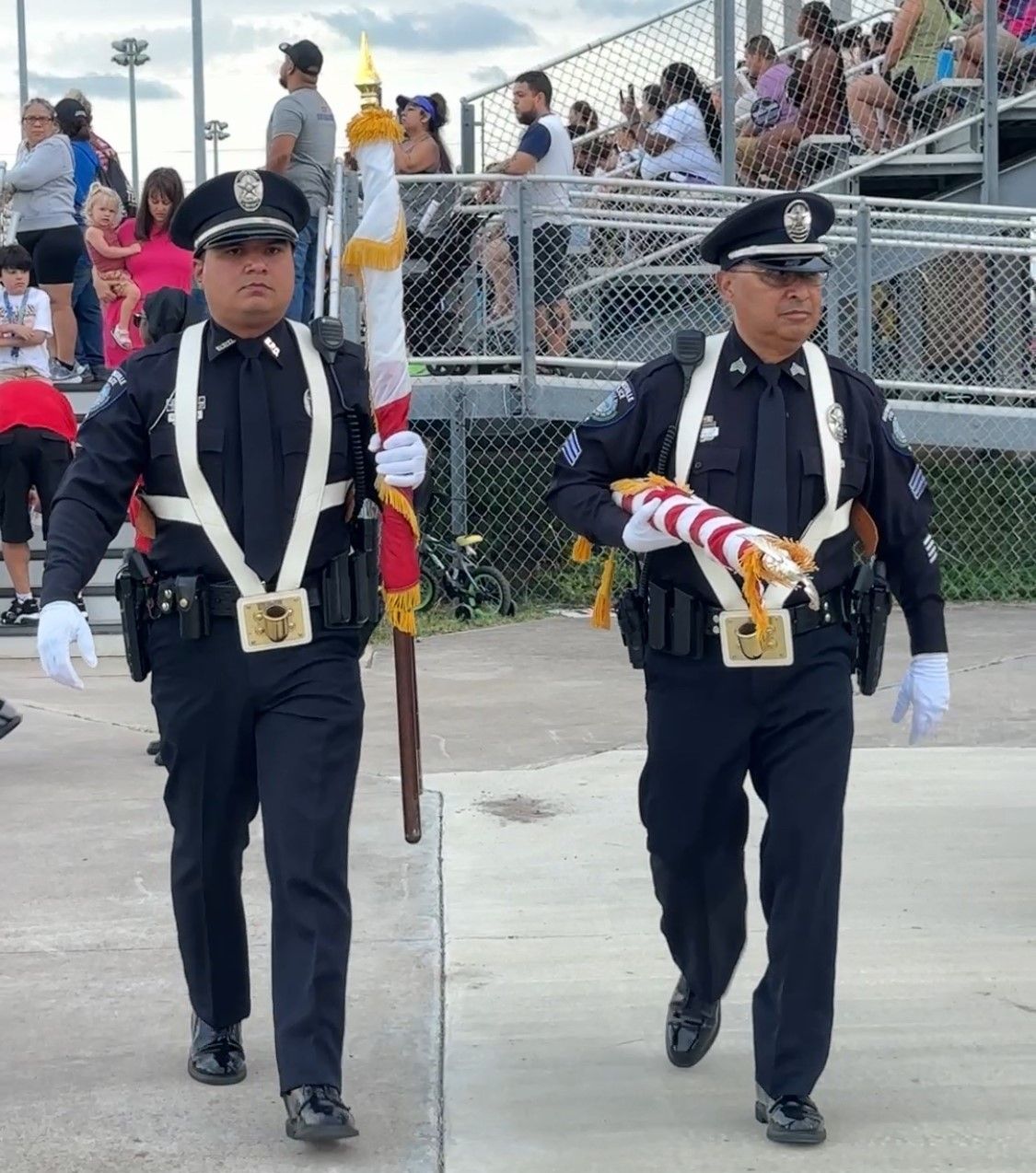 Two police officers carrying flags are walking down the street