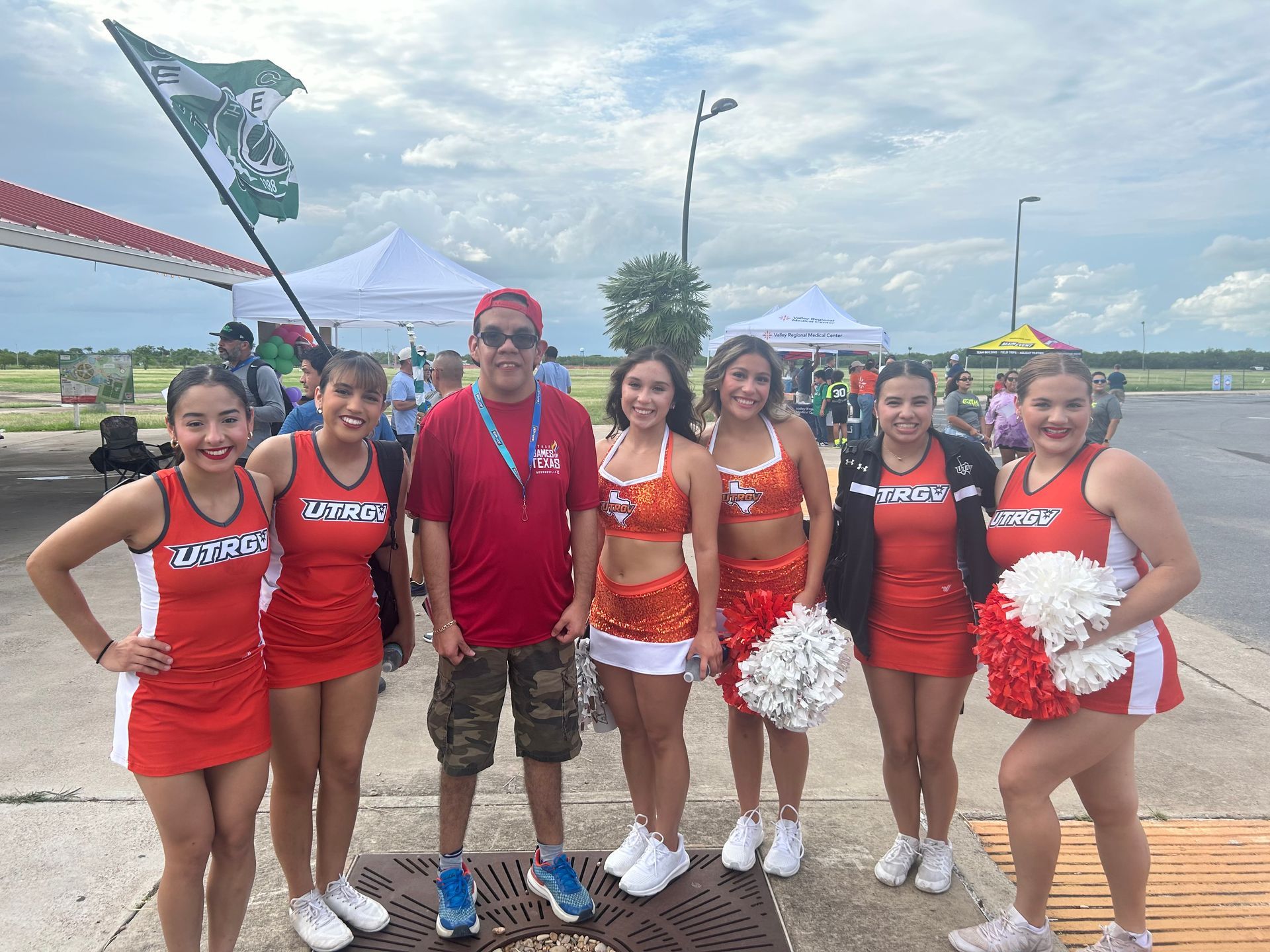 A group of cheerleaders are posing for a picture with a man.