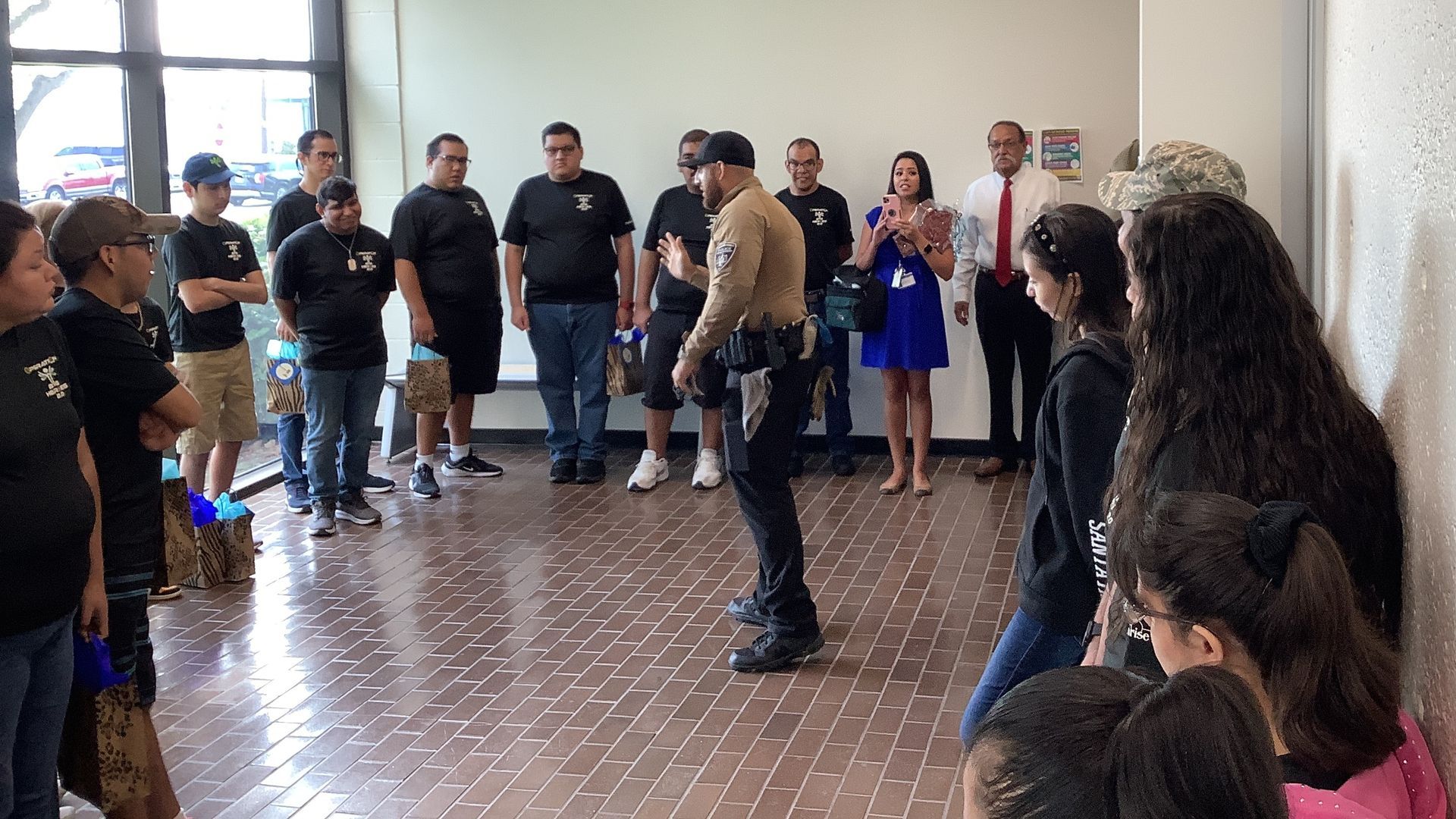 A group of people are standing around a police officer in a room.