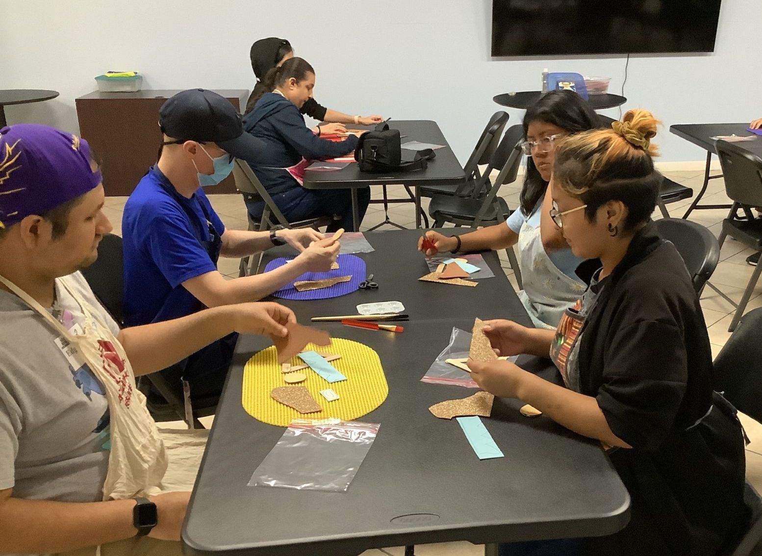 A group of people are sitting at a table making crafts.
