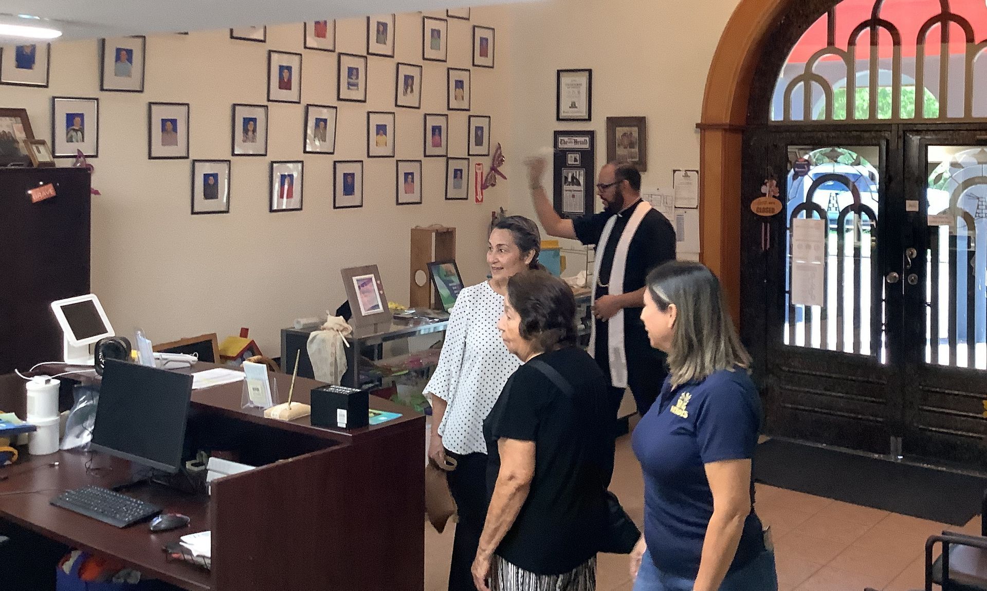 A group of people are standing in a room with pictures on the wall.