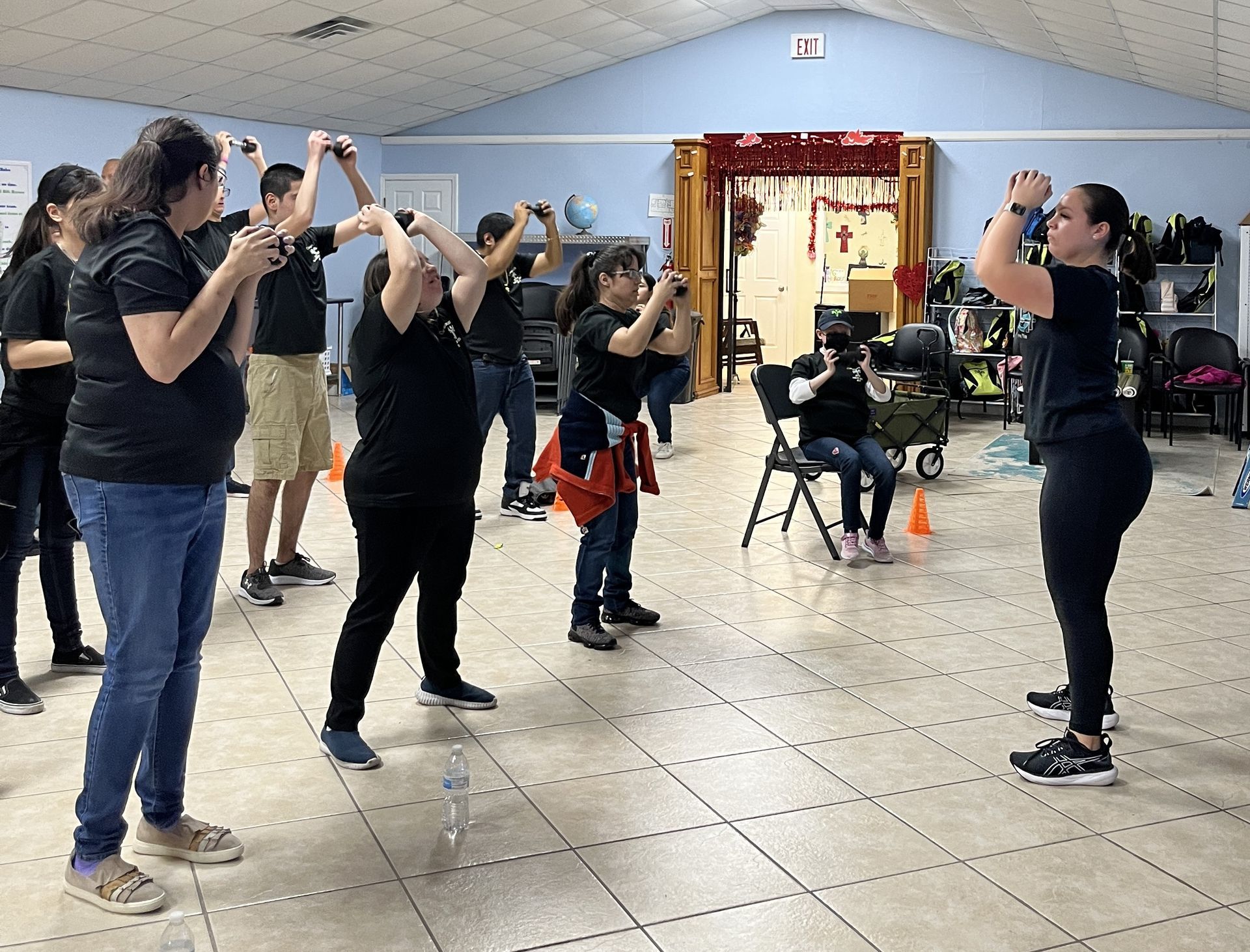 A group of people are standing in a room with their hands in the air