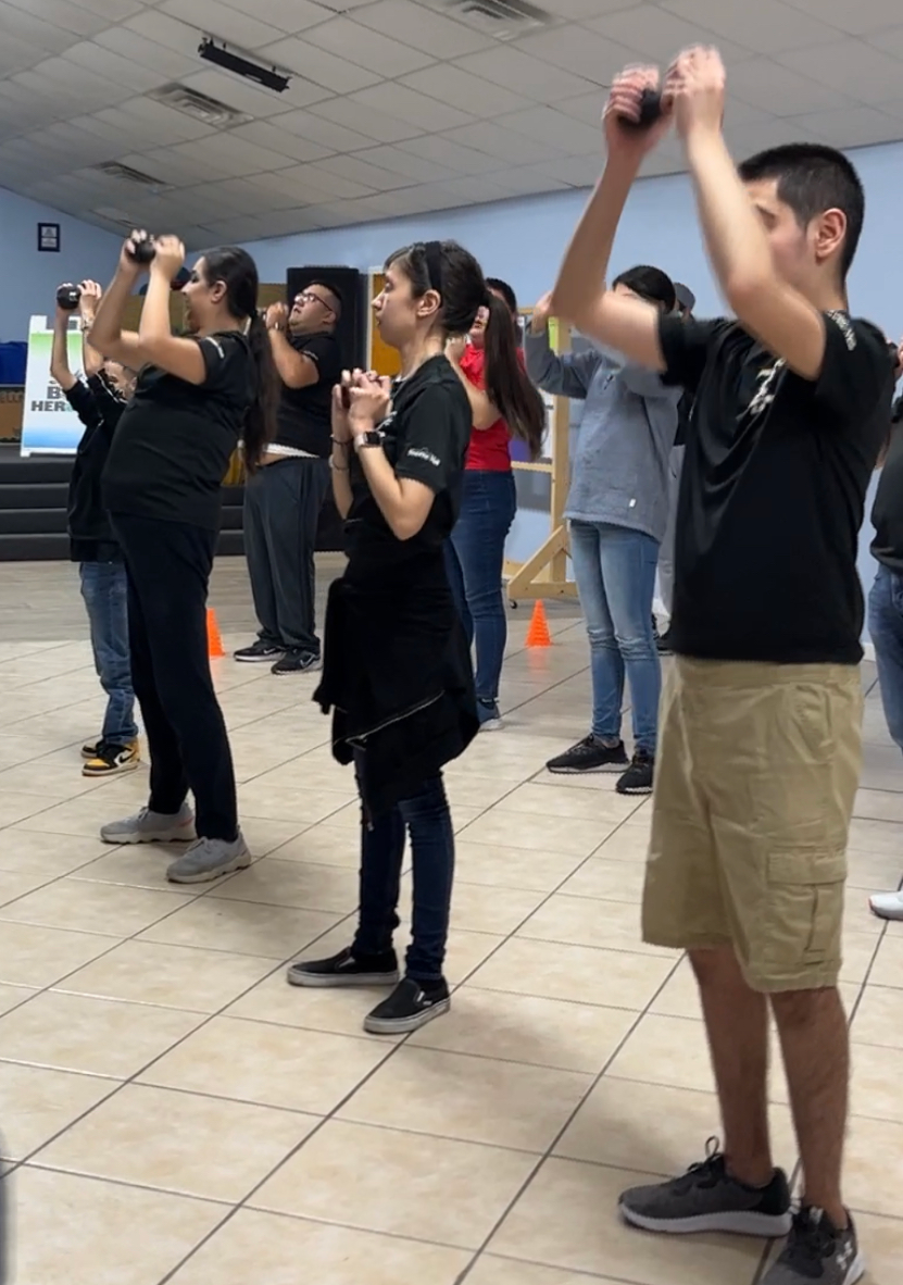 A group of people are standing in a room with their hands in the air