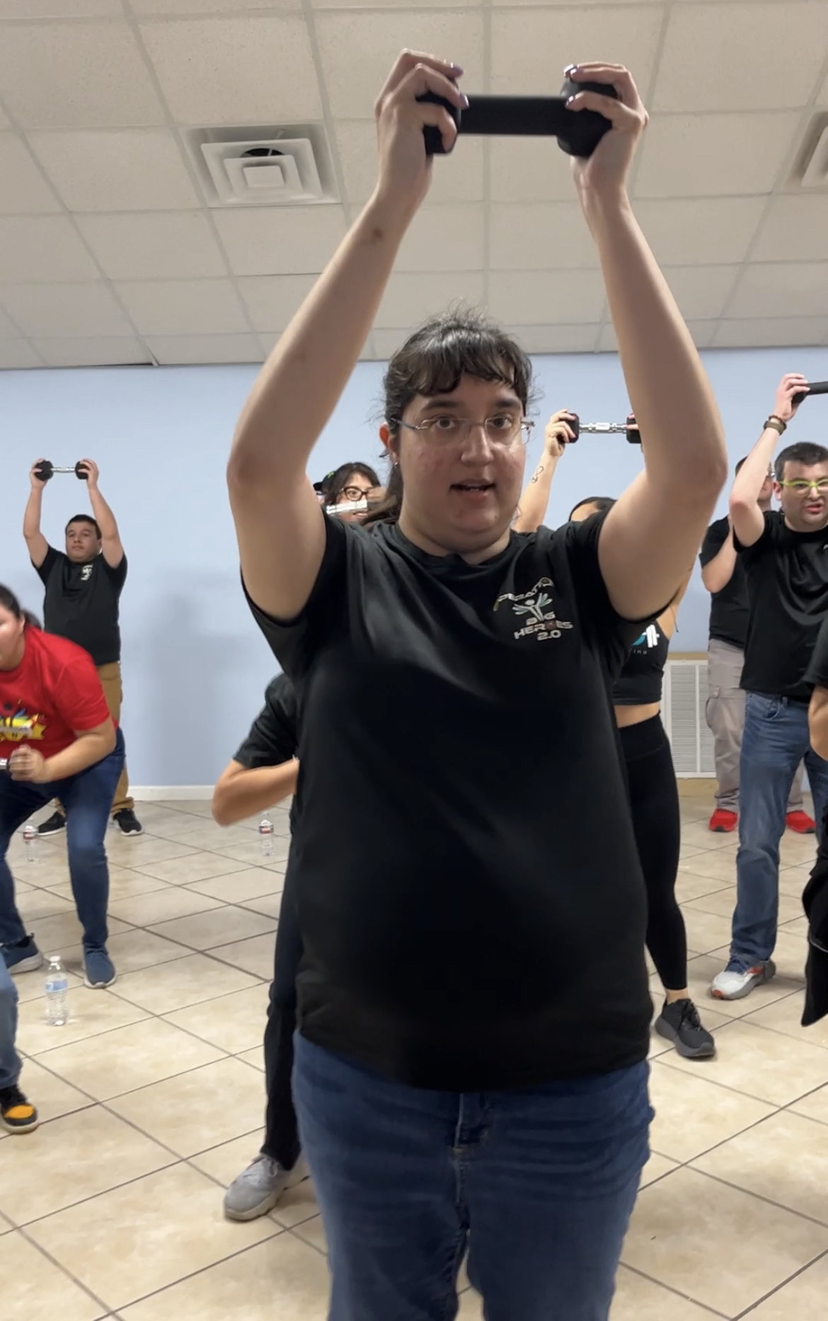 A group of people are standing in a room holding dumbbells in their hands.