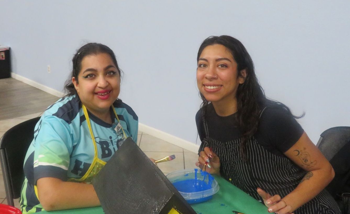 Two women are sitting at a table and smiling for the camera.